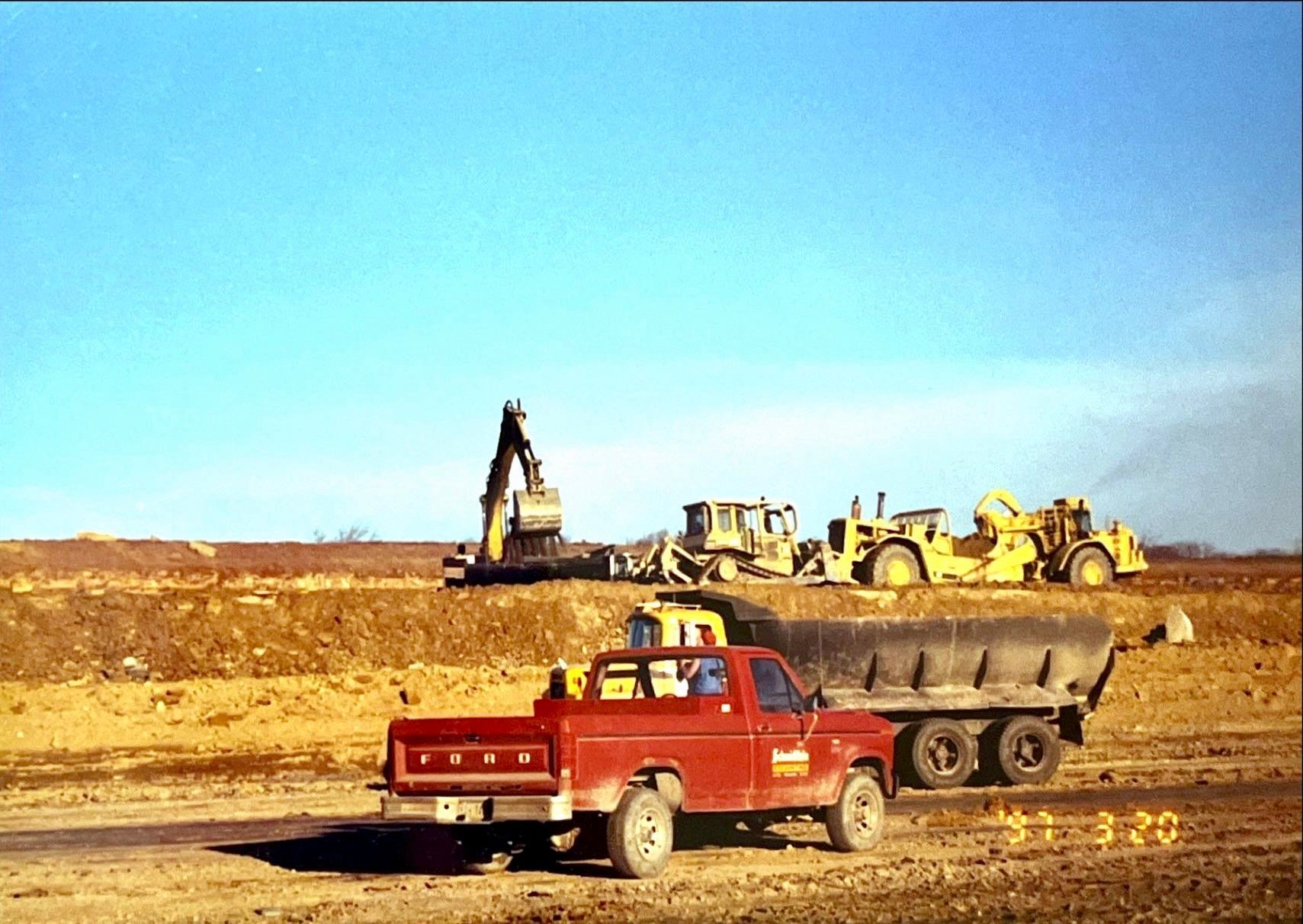 A red ford truck is parked in a dirt field