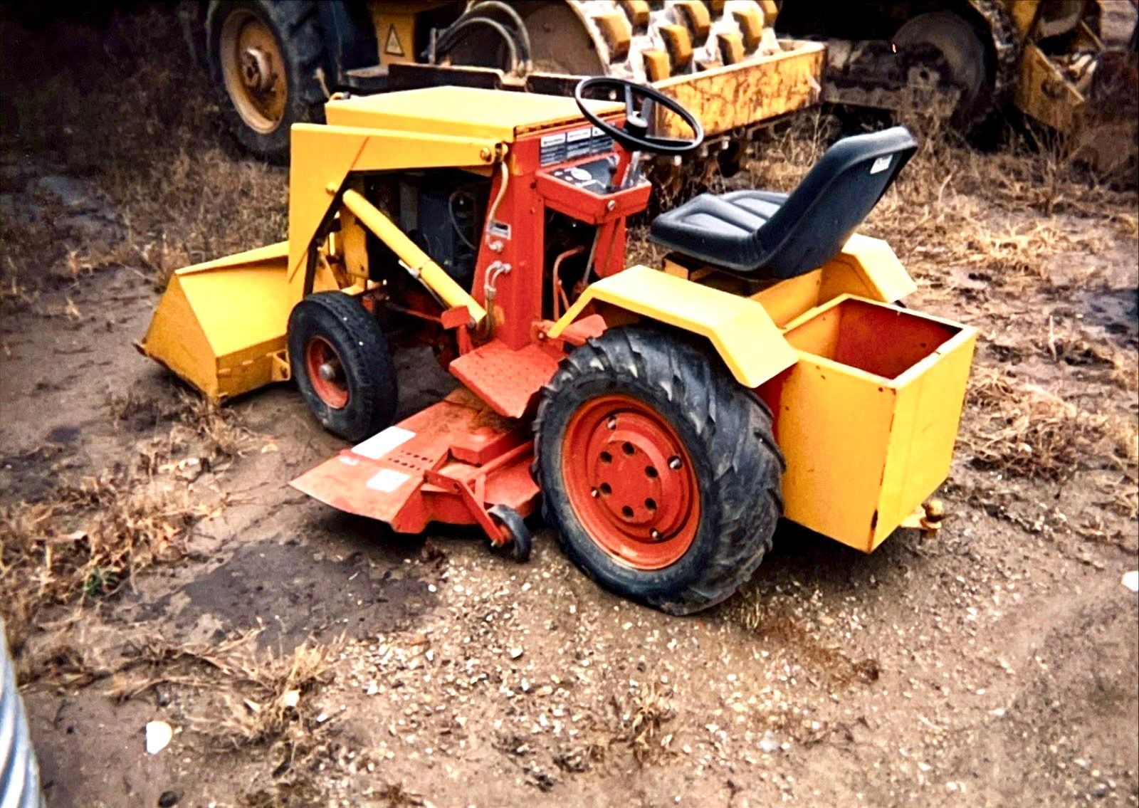 A yellow and red tractor is parked in the dirt