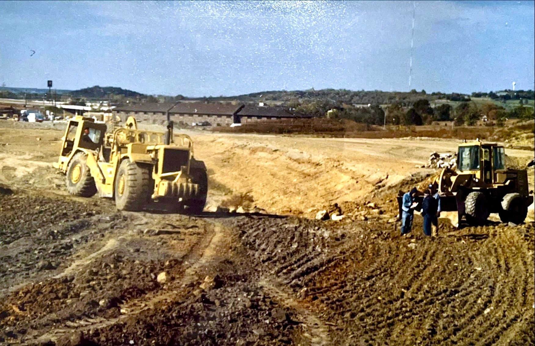 Two bulldozers are working in a dirt field