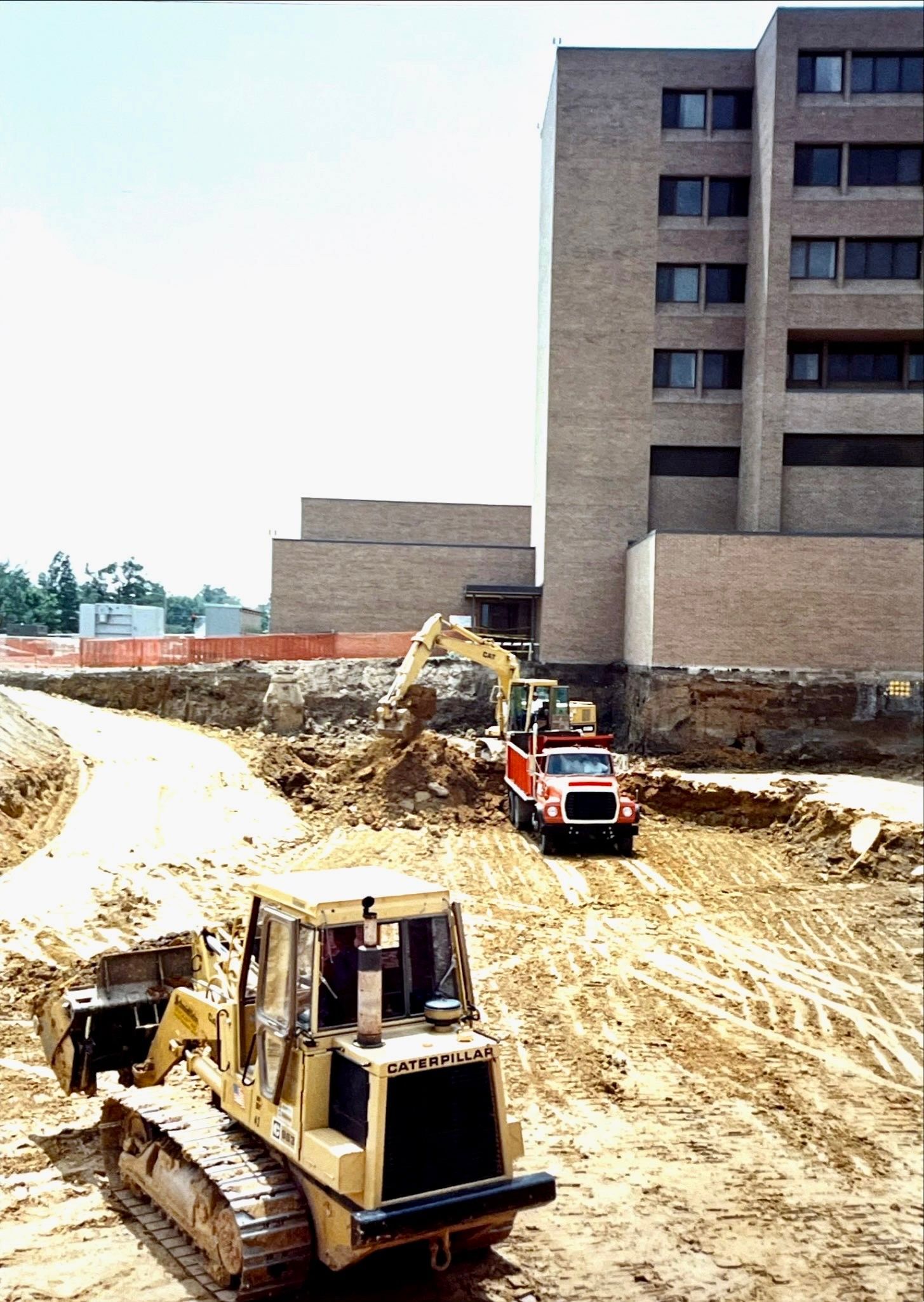 A bulldozer is driving down a dirt road in front of a building