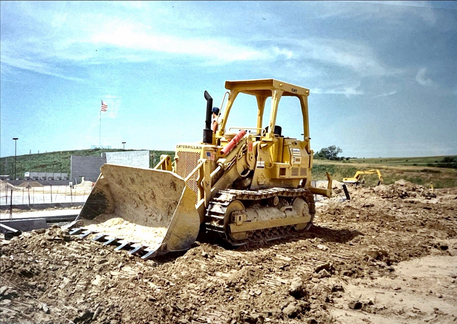 A yellow bulldozer is sitting in the dirt on a construction site