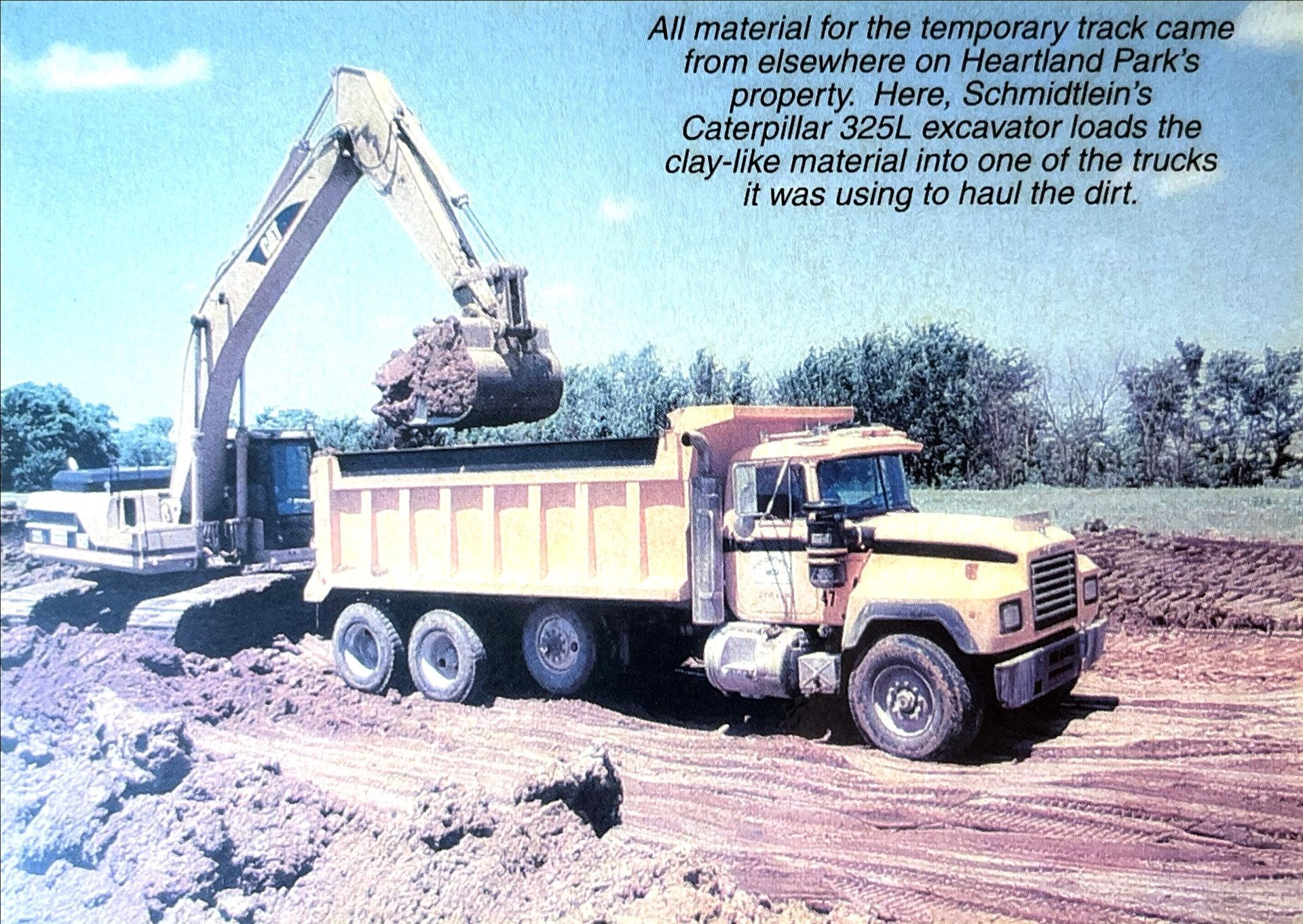 A dump truck is being loaded with dirt by an excavator