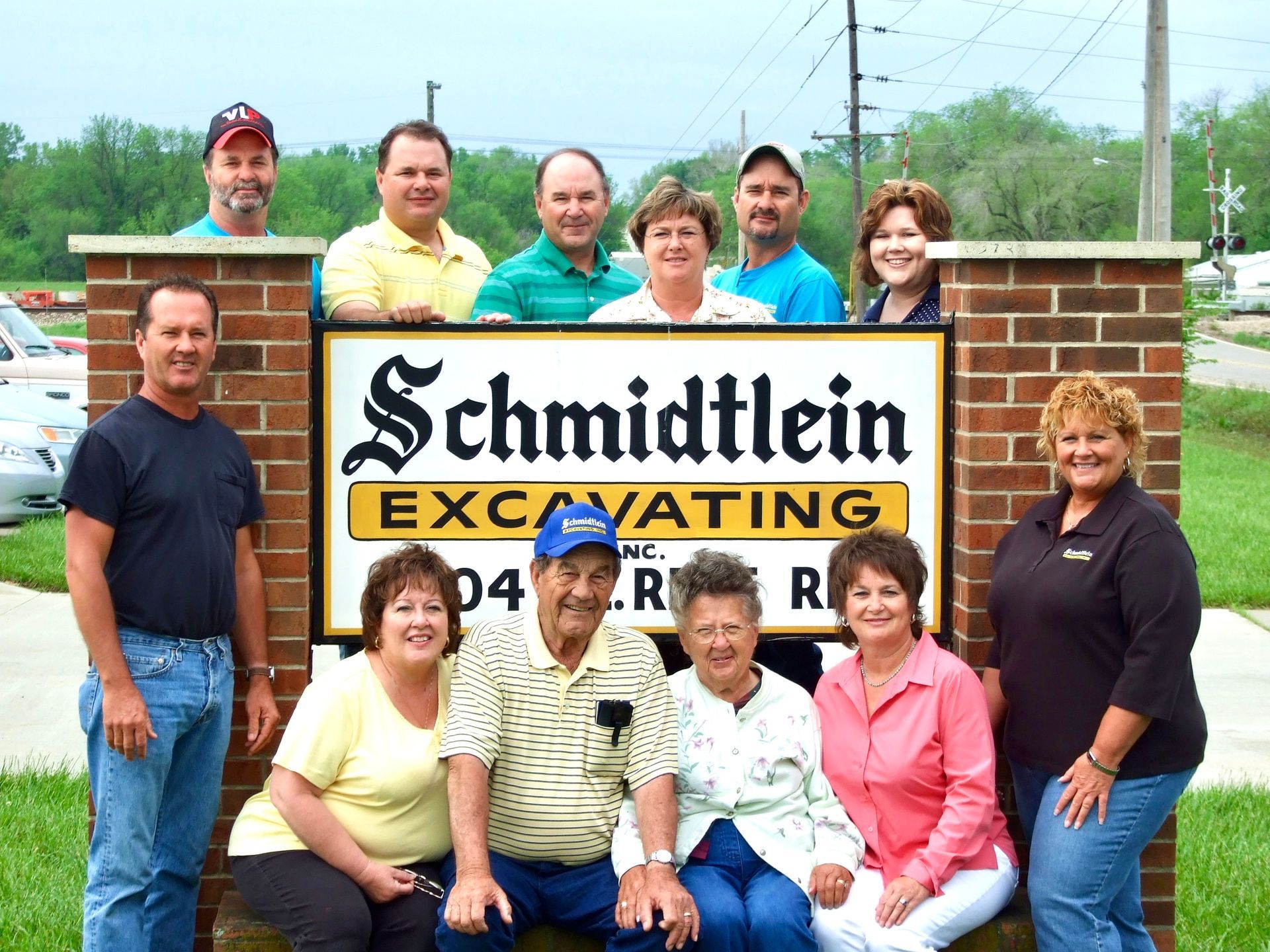 A group of people posing in front of a schmidtlein excavating sign