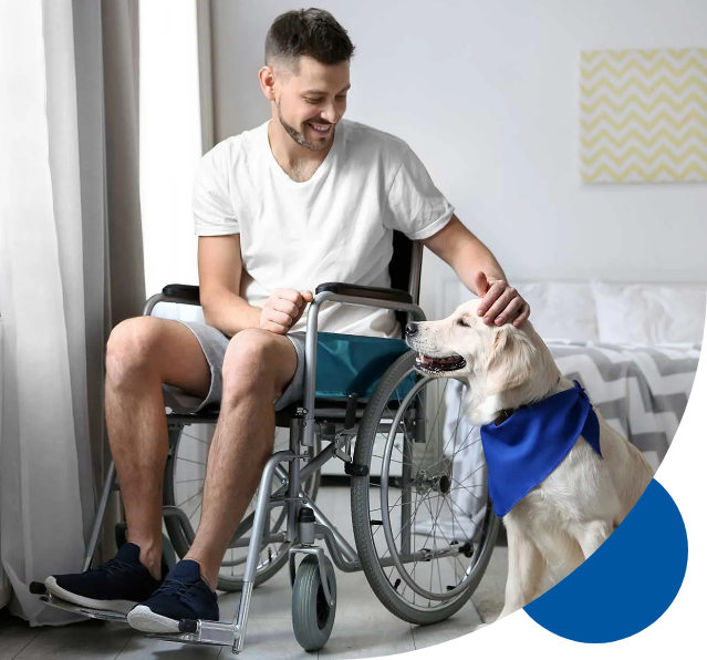 A man in a wheelchair is petting a dog.