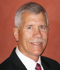 A man in a suit and tie is smiling for the camera