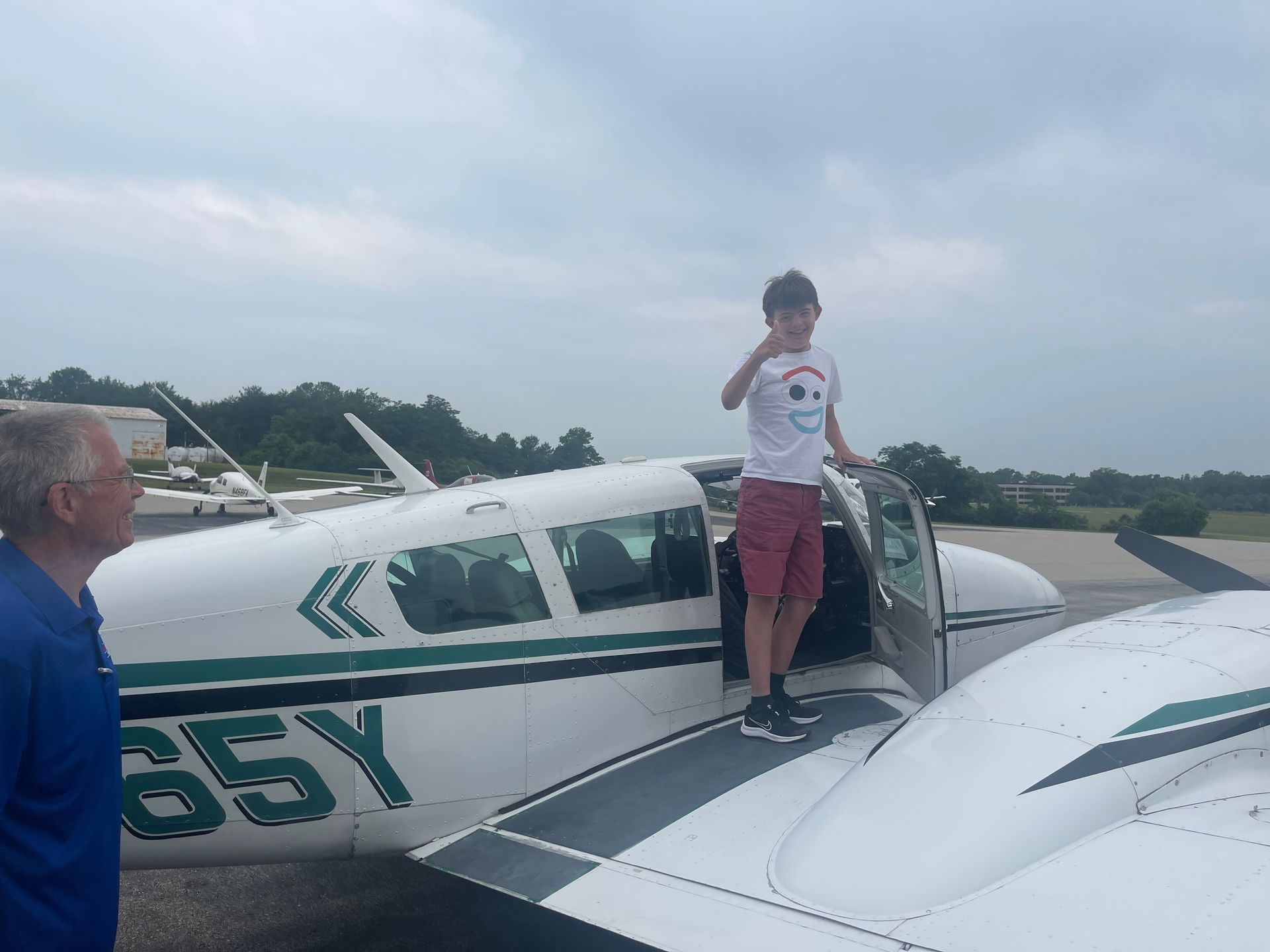 Disabled teen on the wing of a general aviation aircraft with volunteer pilot