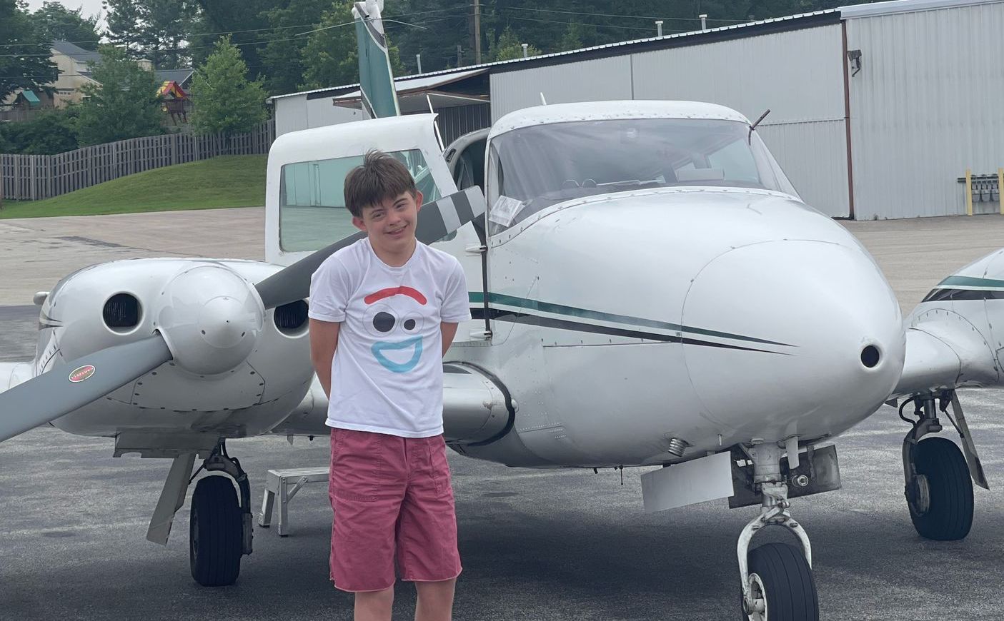 Disabled teen in front of volunteer pilot's aircraft on the way to Victory Junction