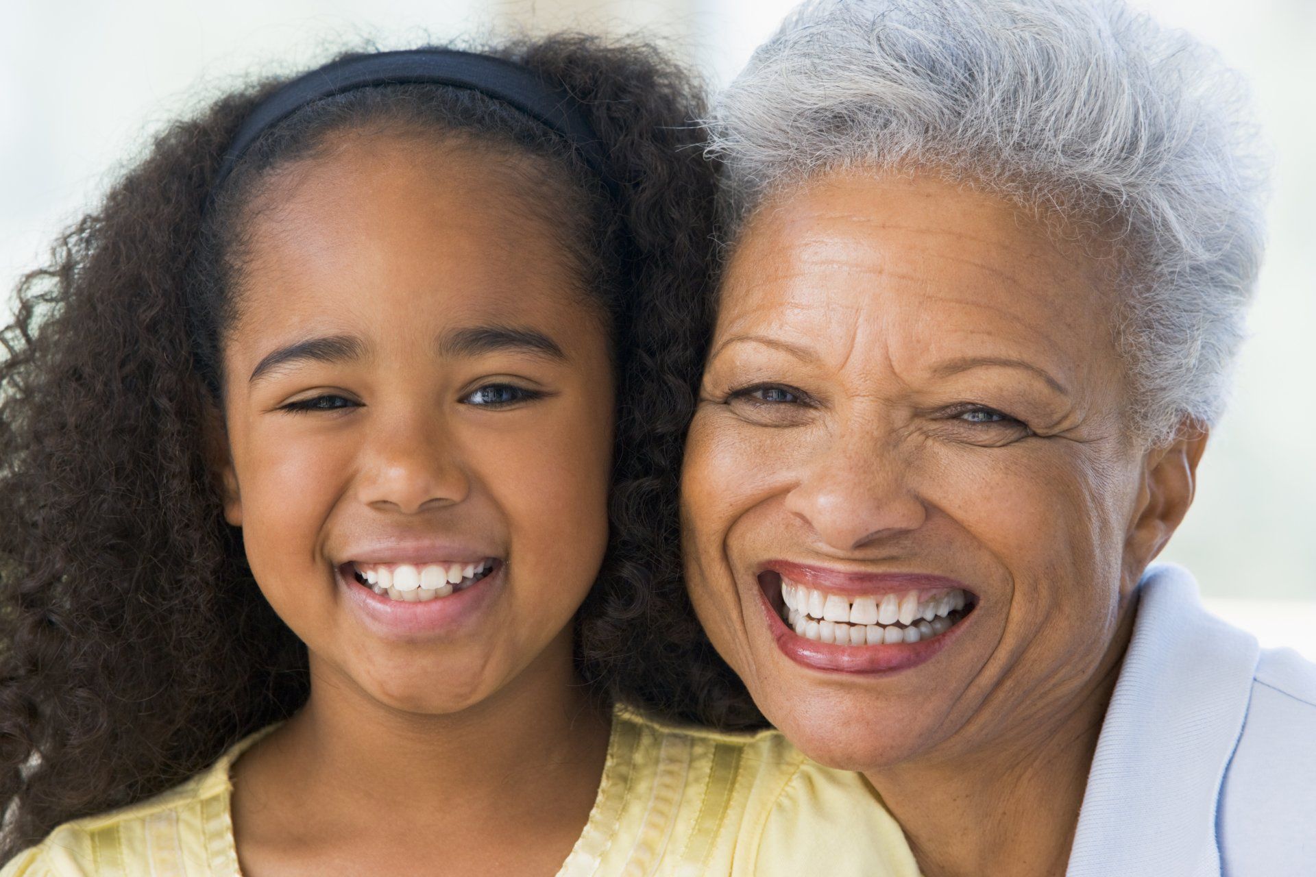 An elderly woman and a young girl are smiling for the camera.