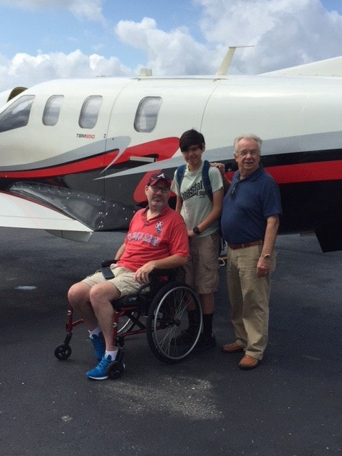 A man in a wheelchair is standing in front of a plane