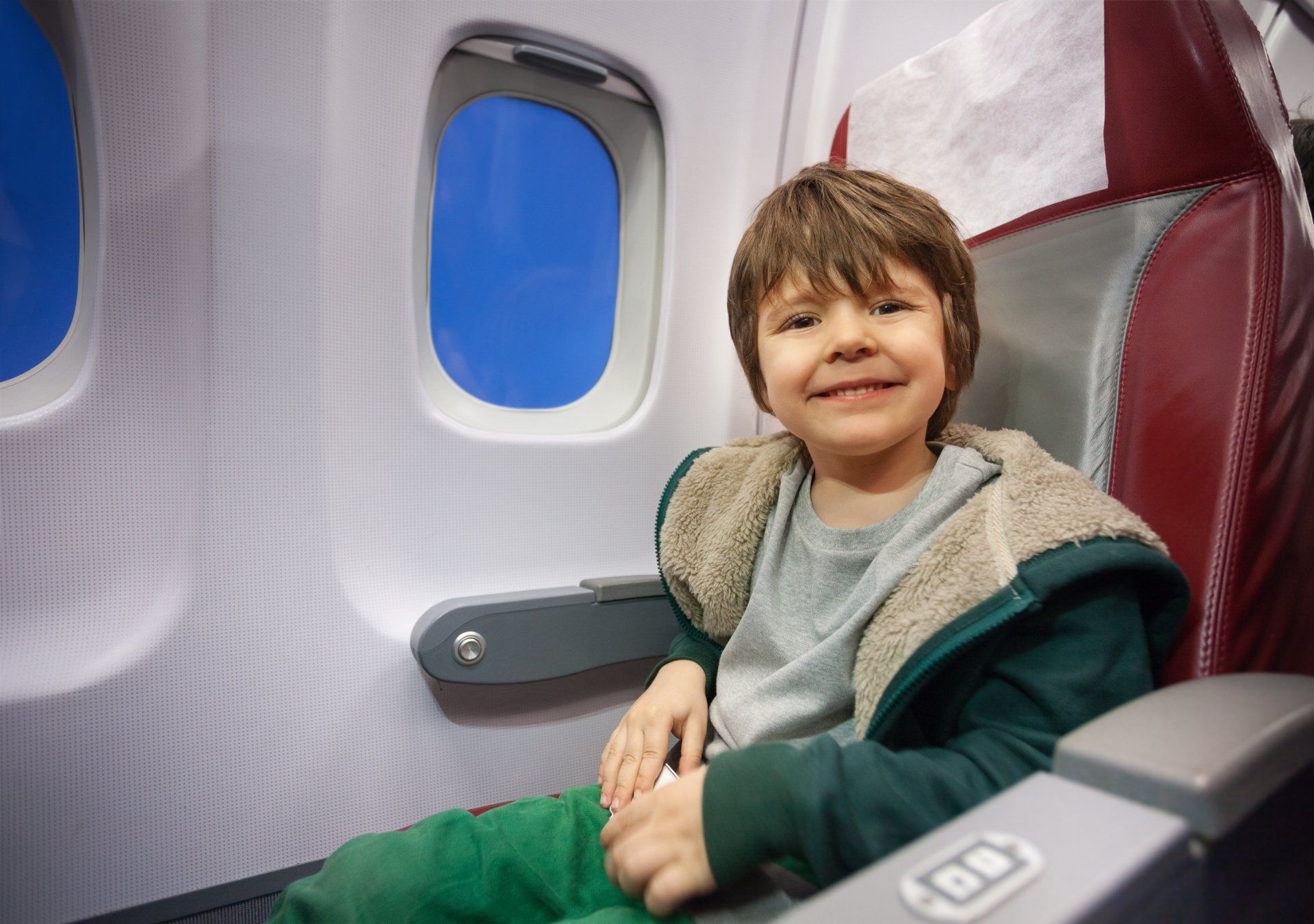 A young boy is sitting in an airplane seat.