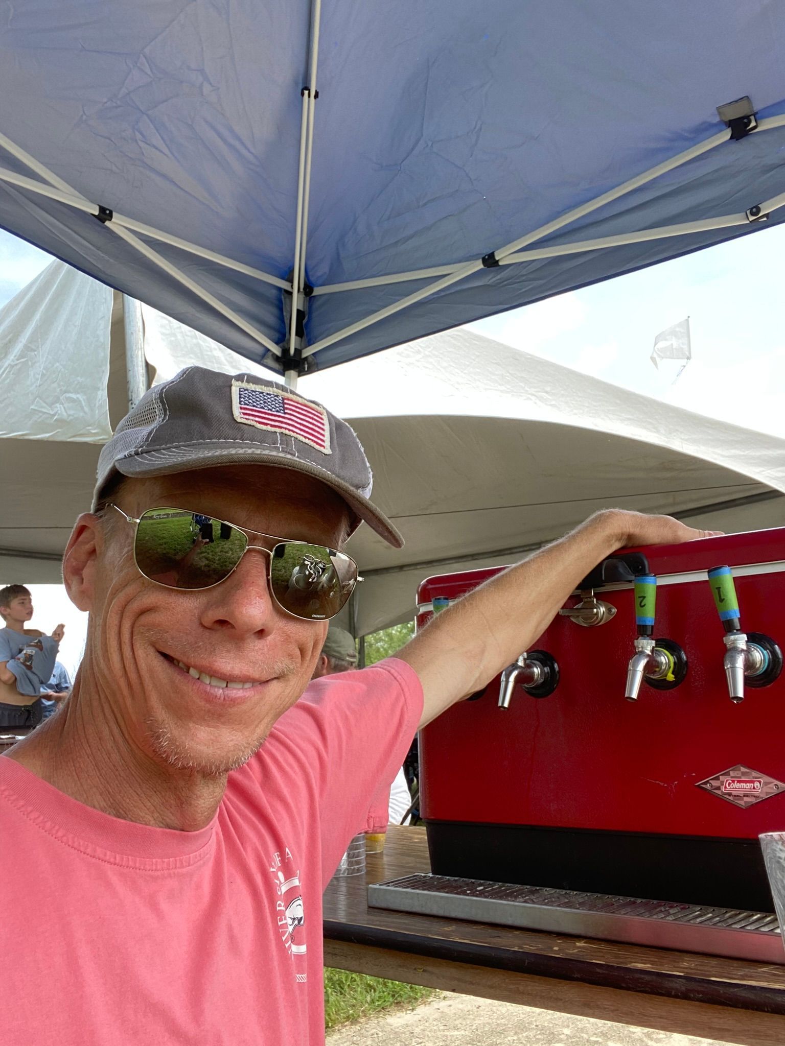 A man stands next to beer taps abd smiles at the ICL Family Picnic.