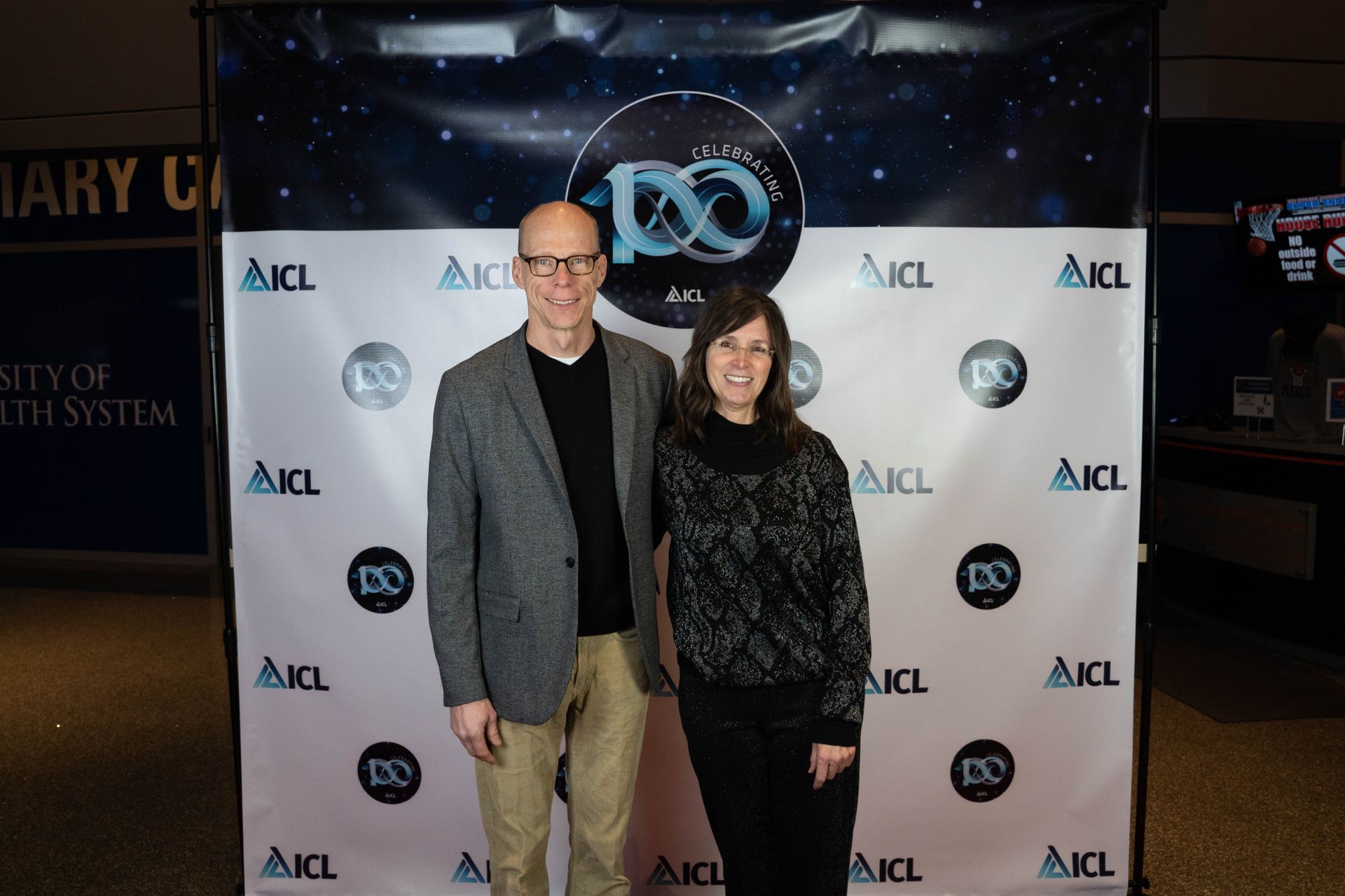 two employees standing at an ICL 100 year aniversary party
