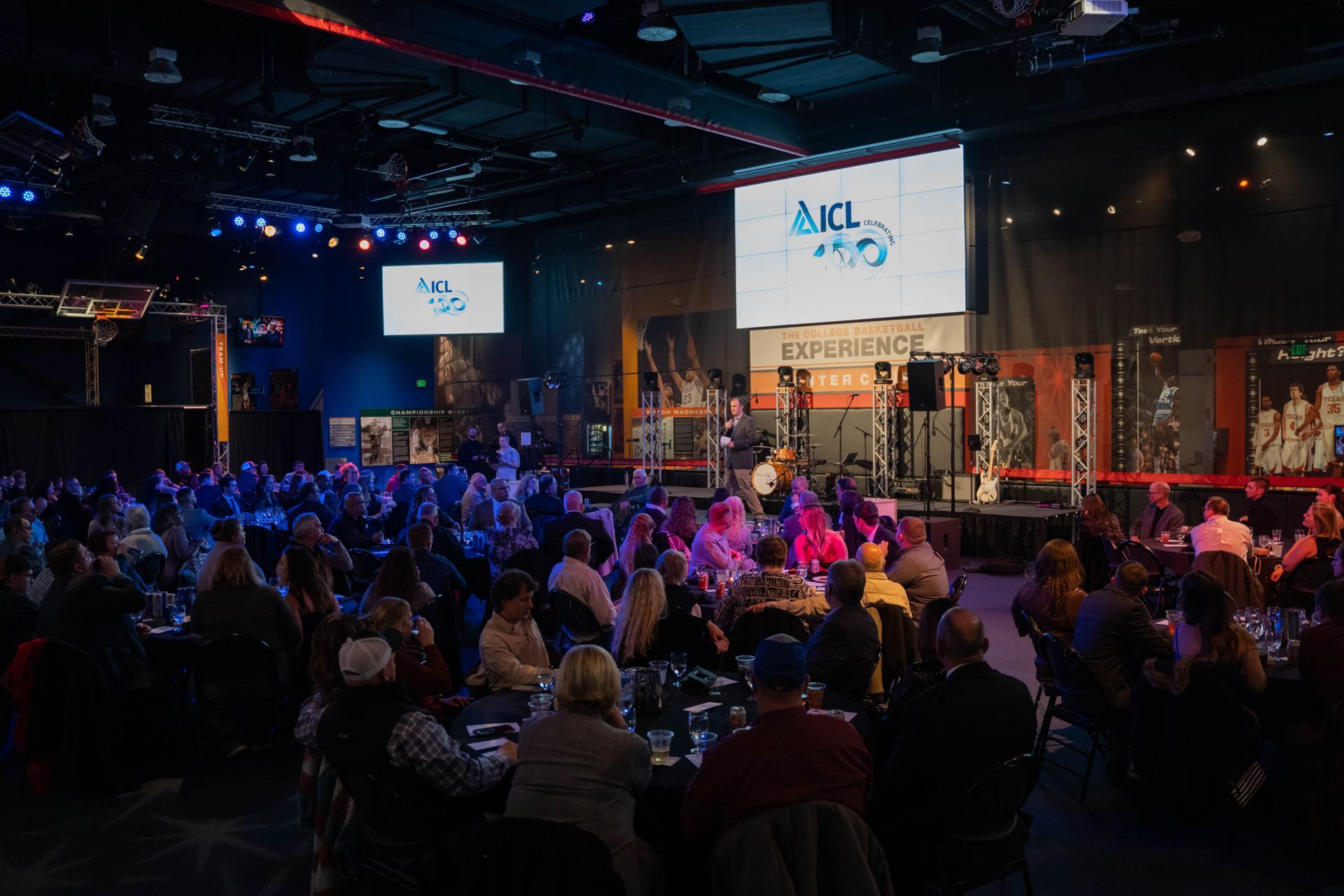 a large group of people are sitting at tables in a large room at an icl event .