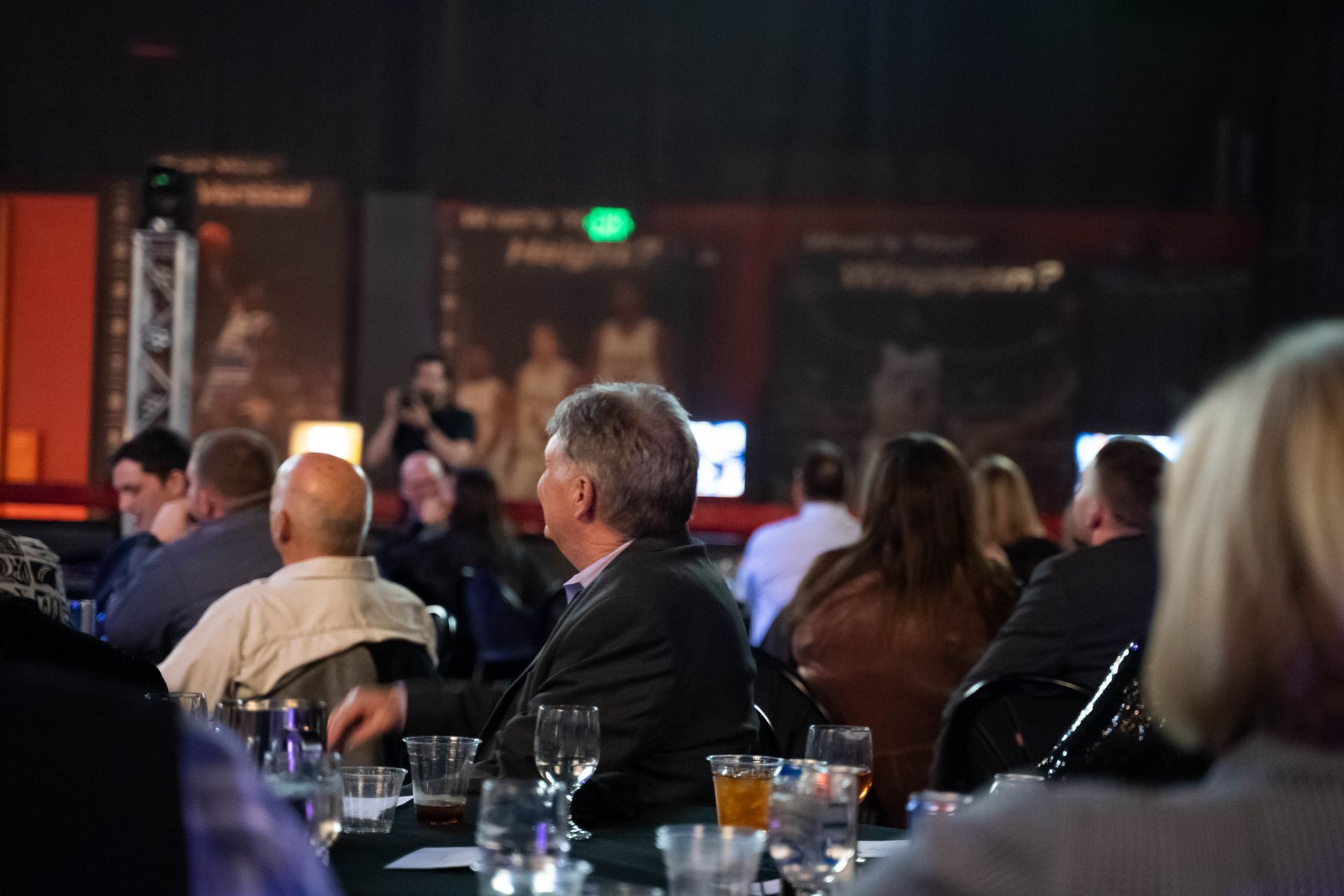 People sit at tables and listen to a speaker at the ICL party.
