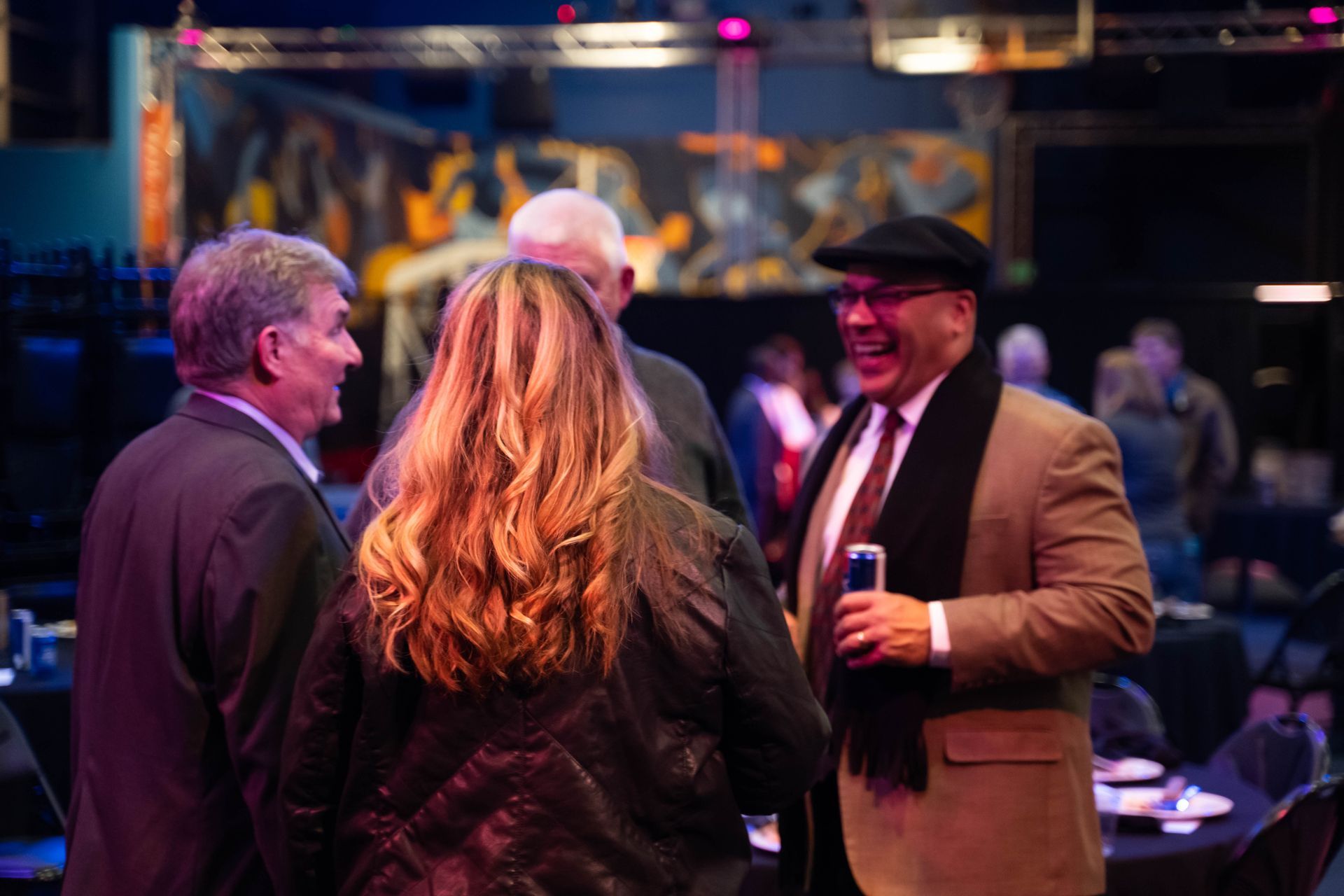 Four people are laughing as they stand around at the ICL party.