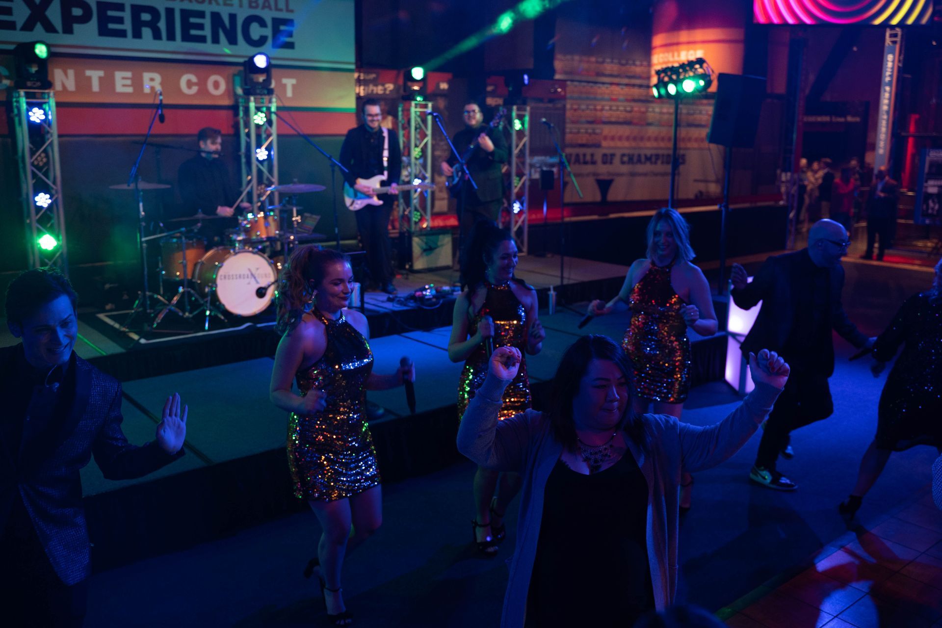 Women are standing in gold sequence dresses and entertaining the crowd at the party.