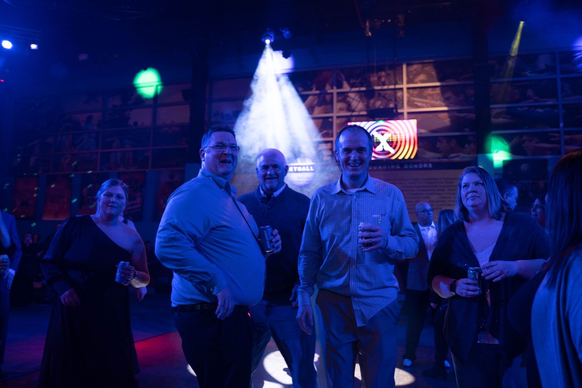 Two men have drinks in their hands and are smiling.