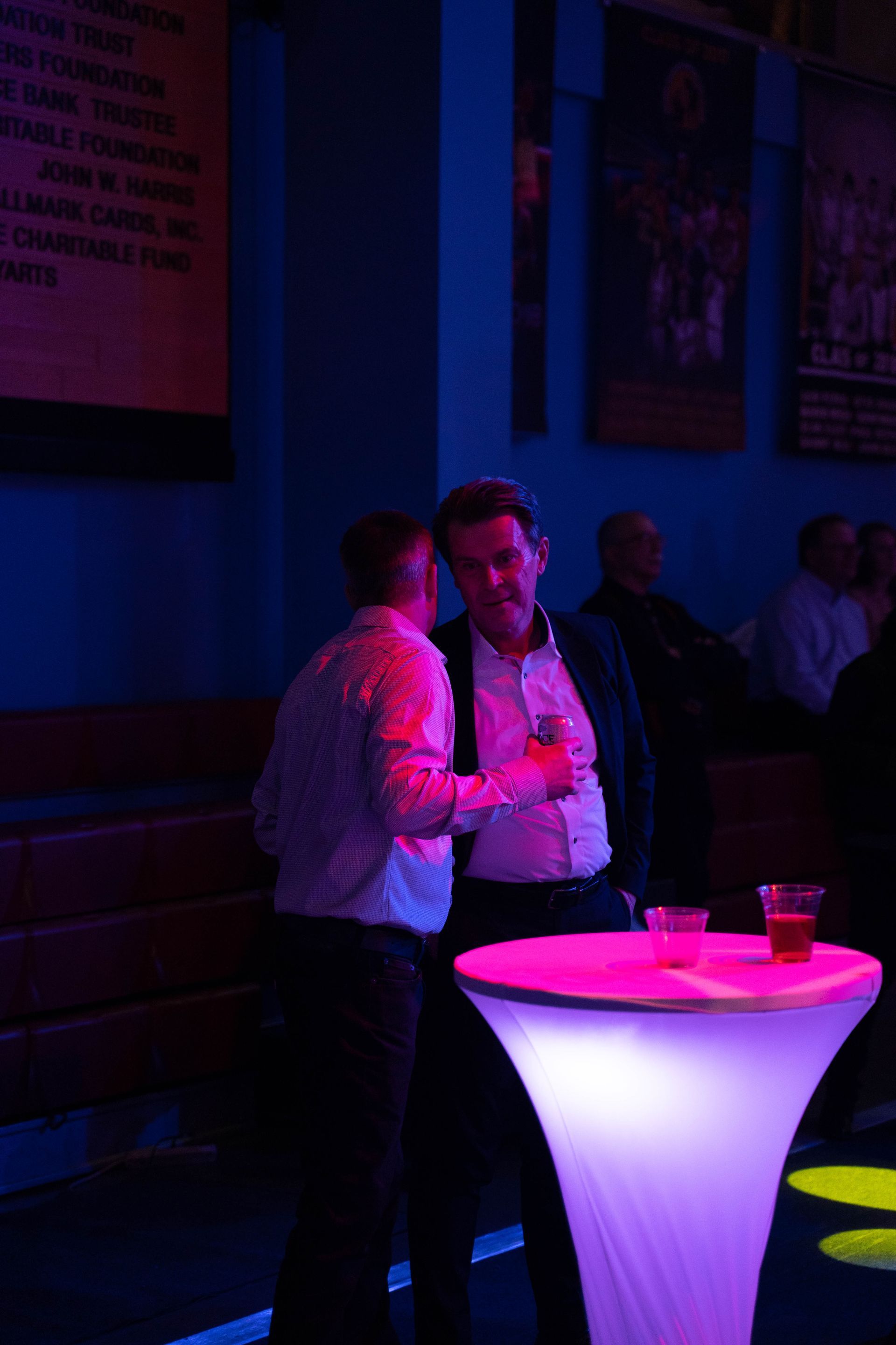 Two men are standing in the corner of ICL's 100 year anniversary party.