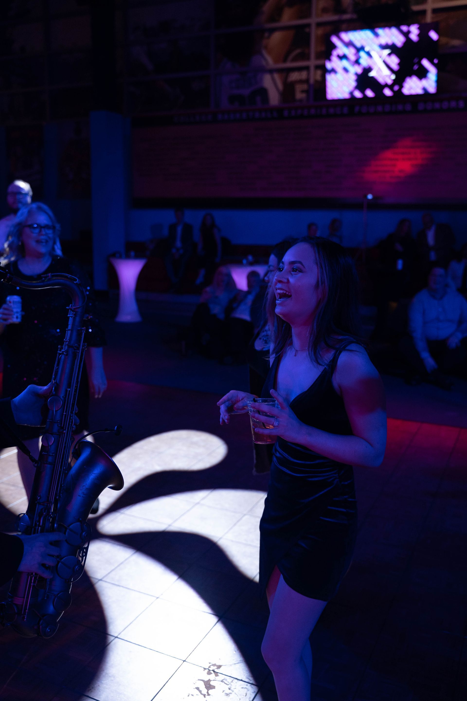 A woman is standing in front of the sax player and smiling.