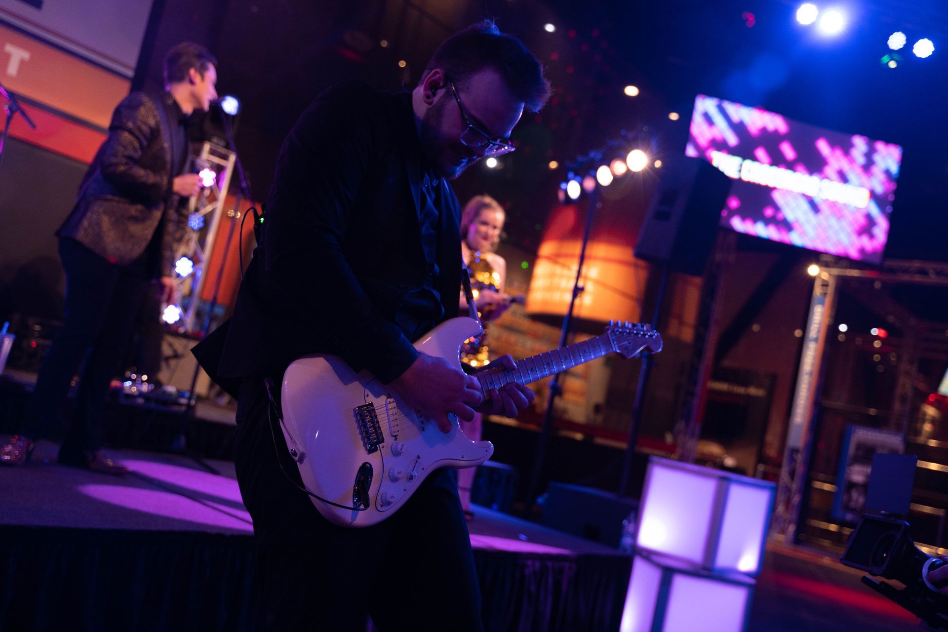 A close up of the guitar player who is standing on the dance floor