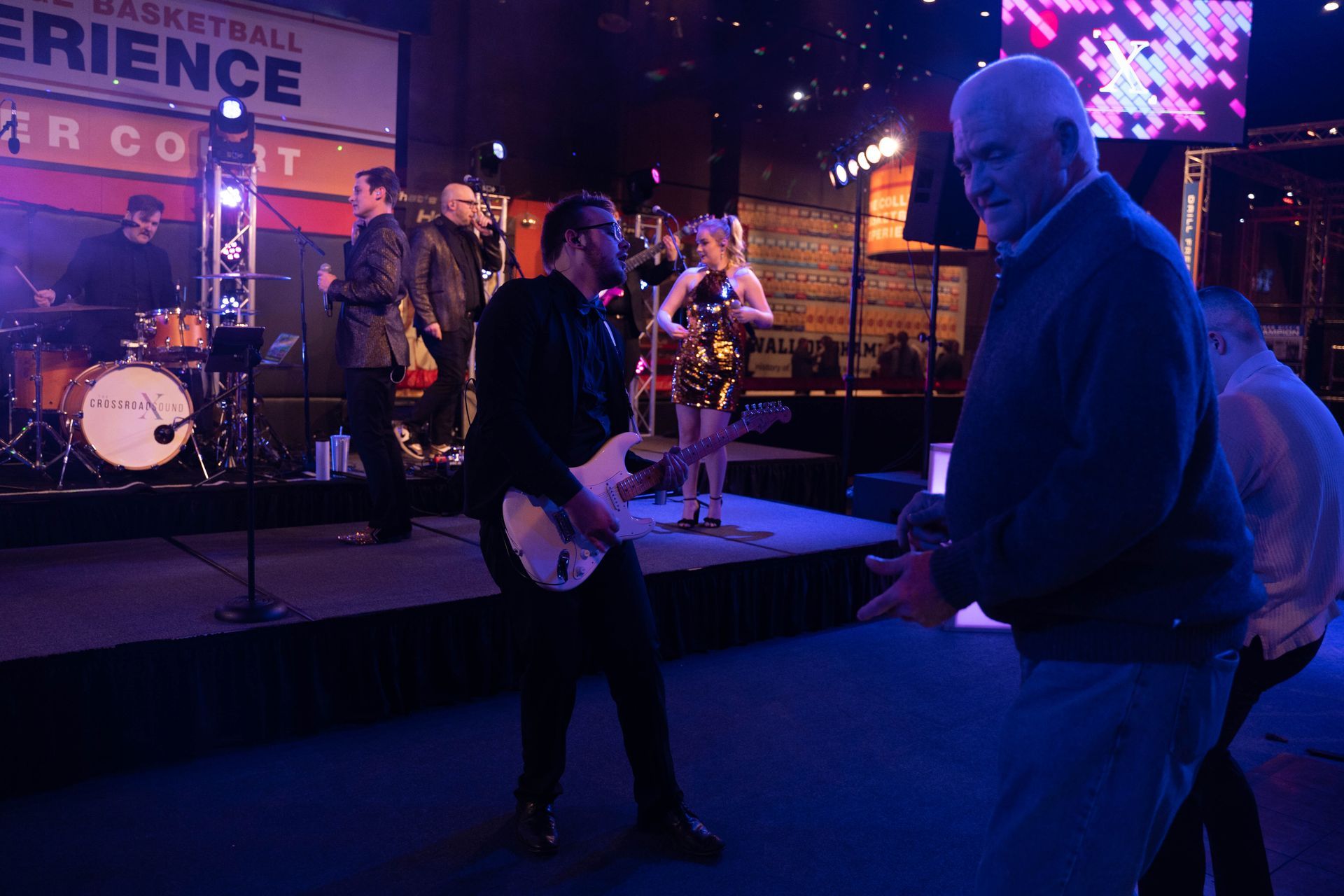 A guitar player from the band has come onto the dance floor with people around him clapping