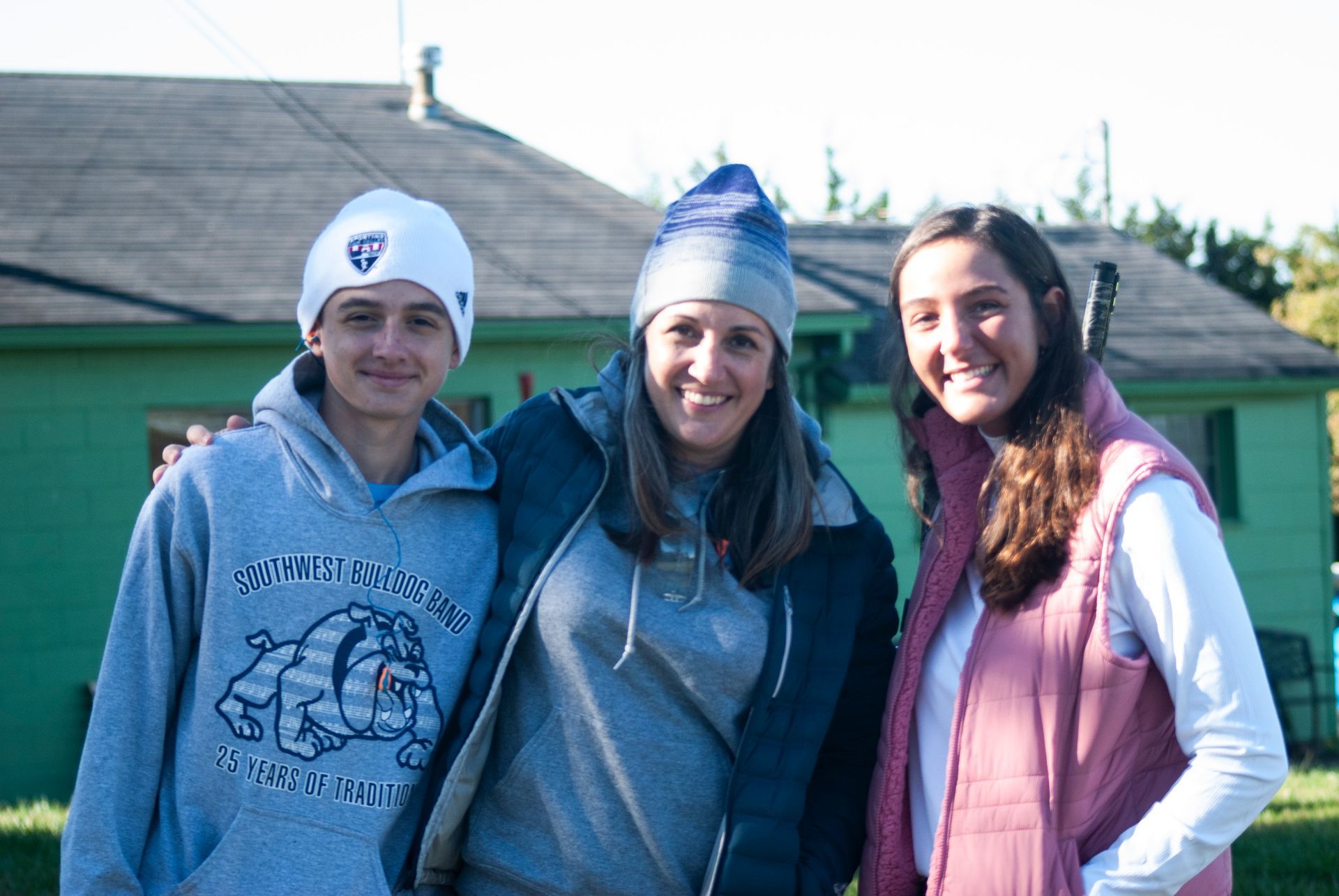 A family of three smile for the camera at the skeet shoot.
