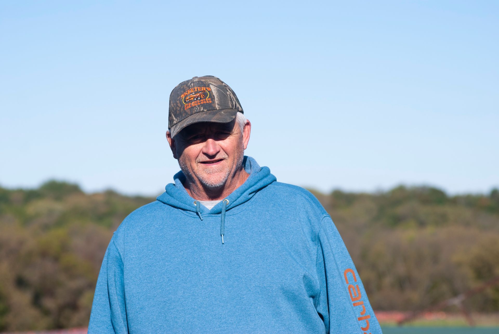 A man standing and smiling at the skeet shoot.