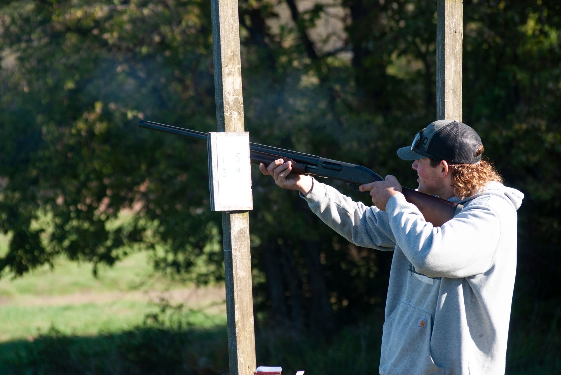 A man is standing and shooting a gun at the skeet shoot.