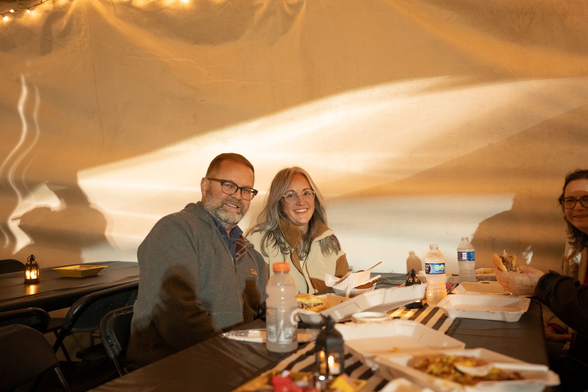 A group of people are sitting at a table with plates of food.