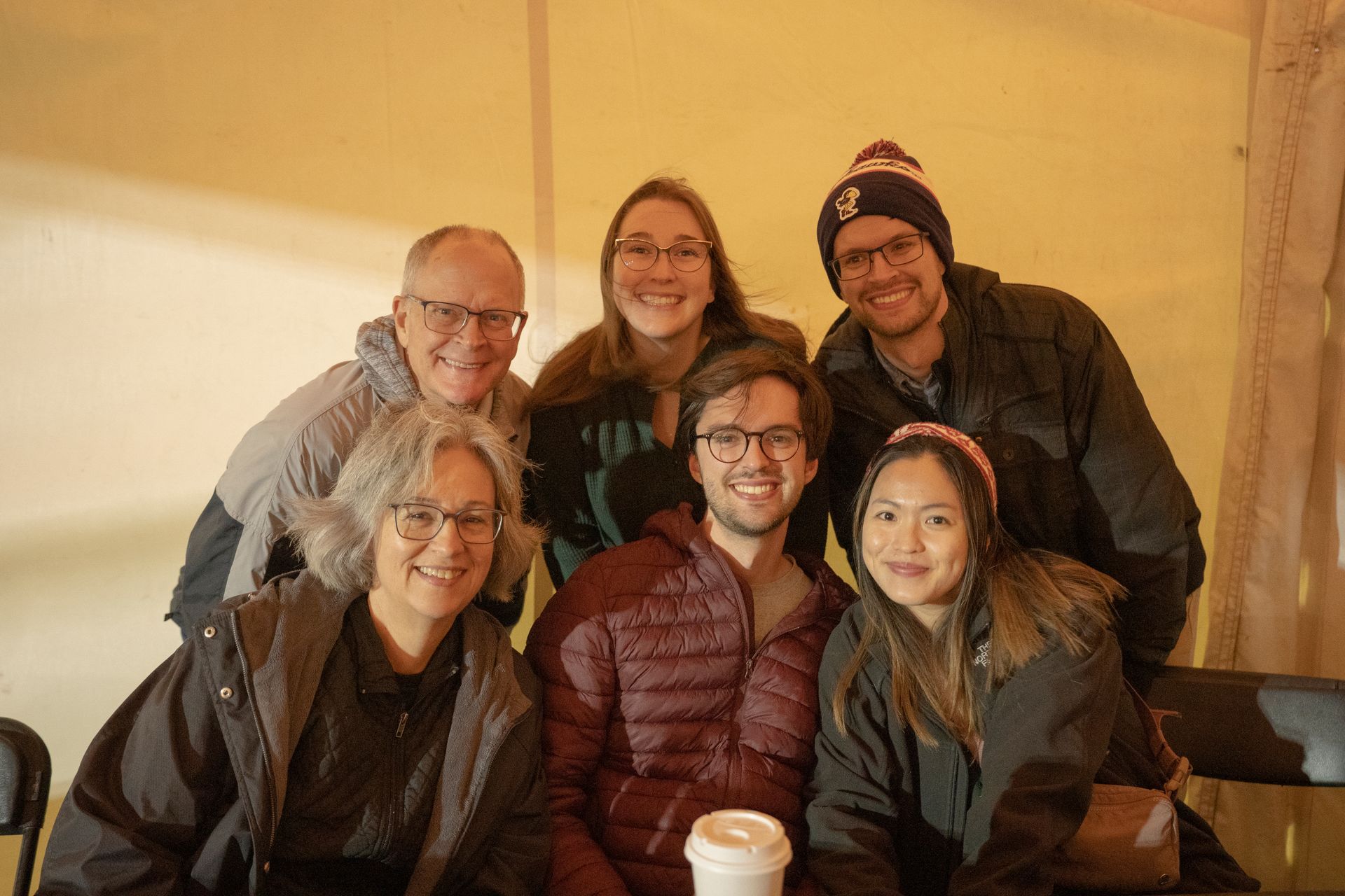A group of people are posing for a picture while sitting at a table.