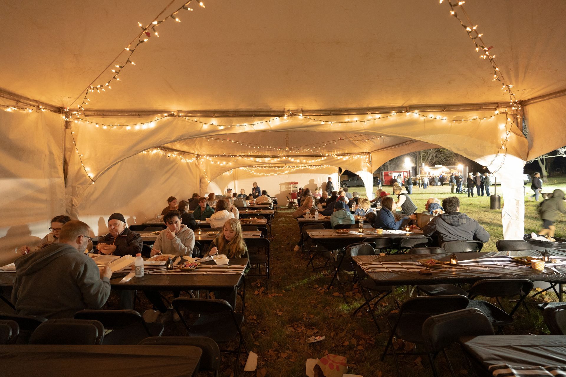 A group of people are sitting at tables under a tent.