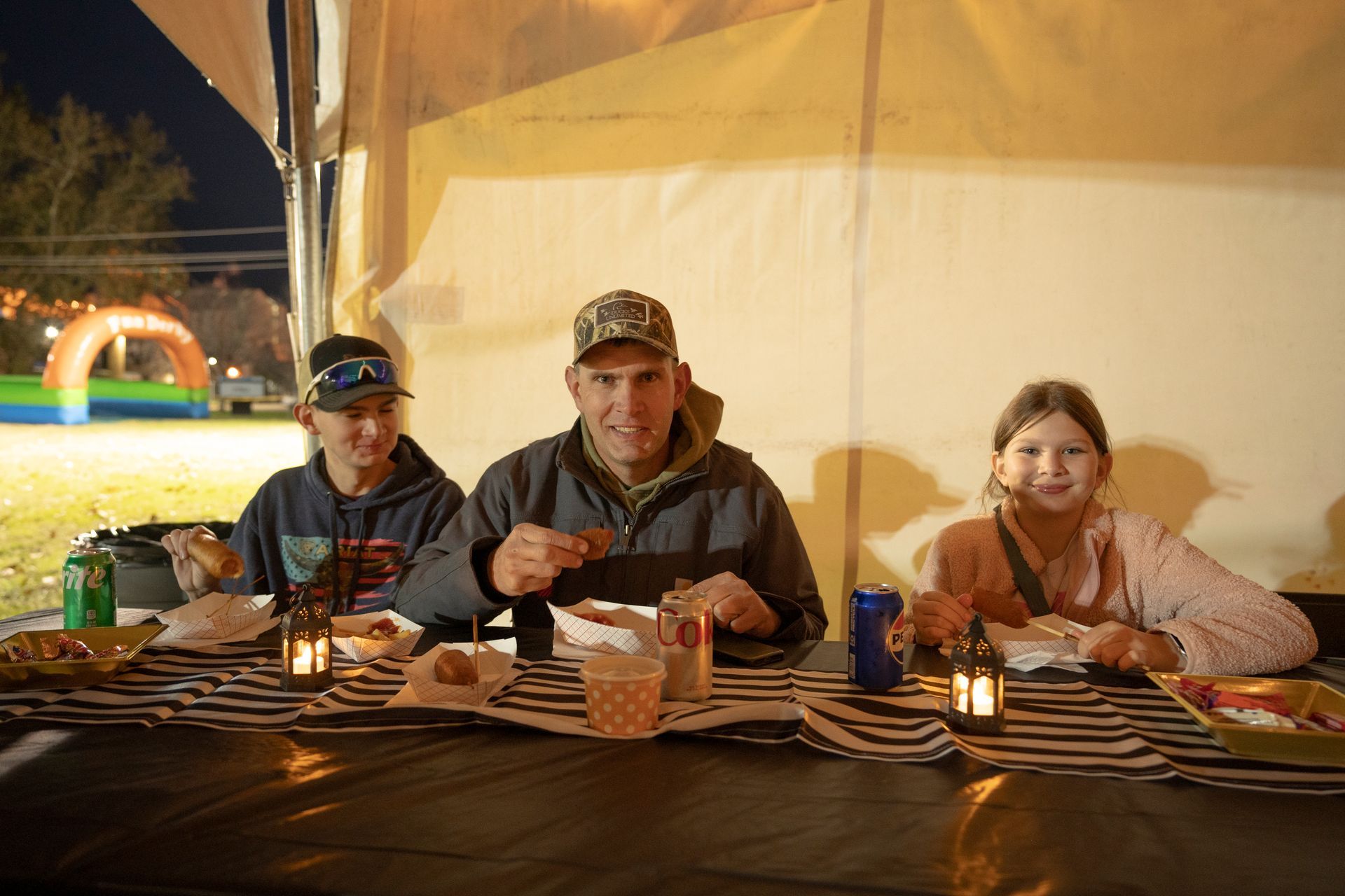 A man and two children are sitting at a table eating food.
