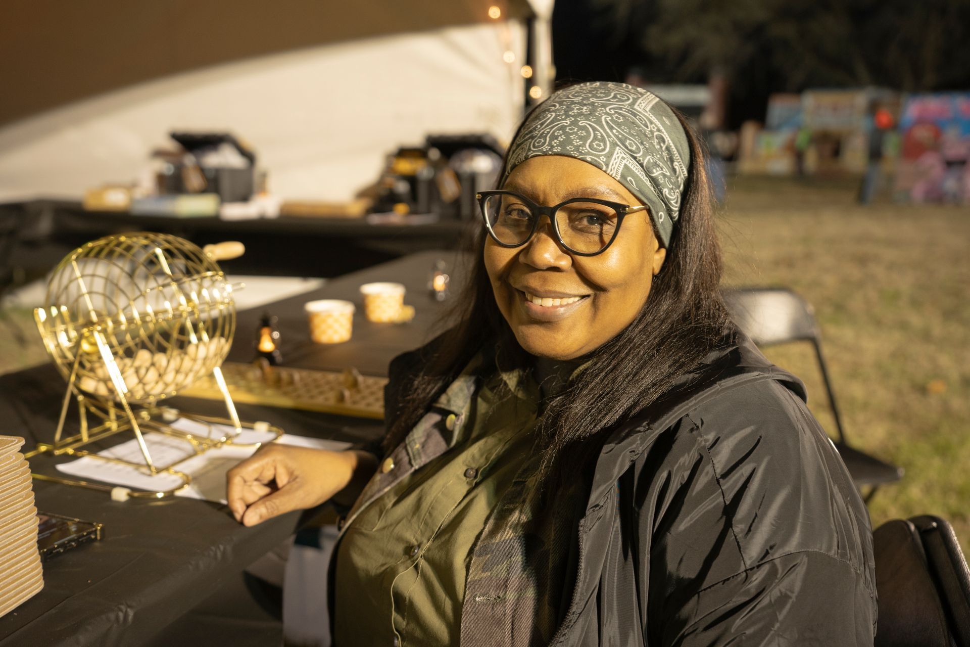 A woman is sitting at a table with a bingo machine.