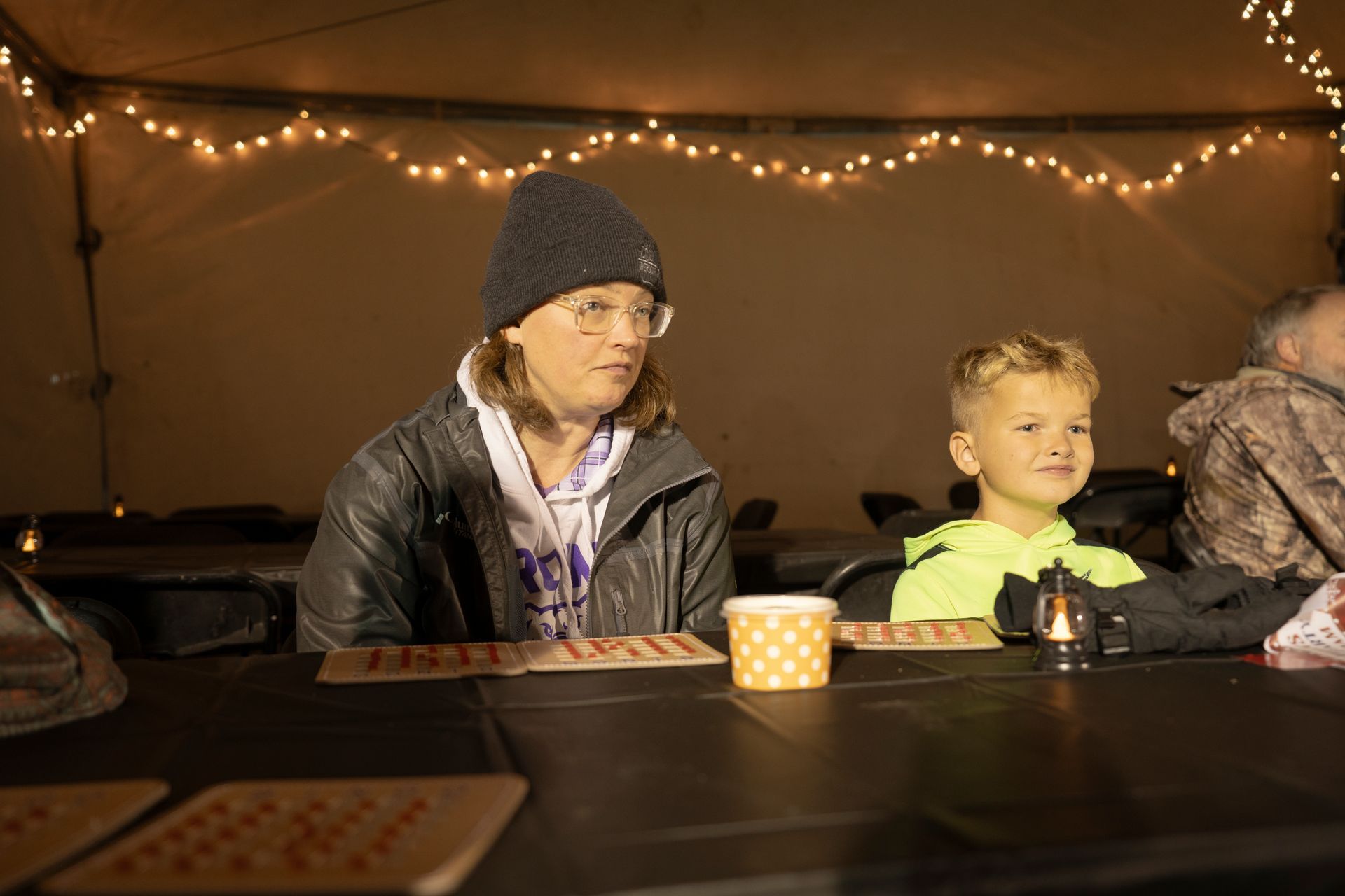 A woman and a child are sitting at a table in a tent.