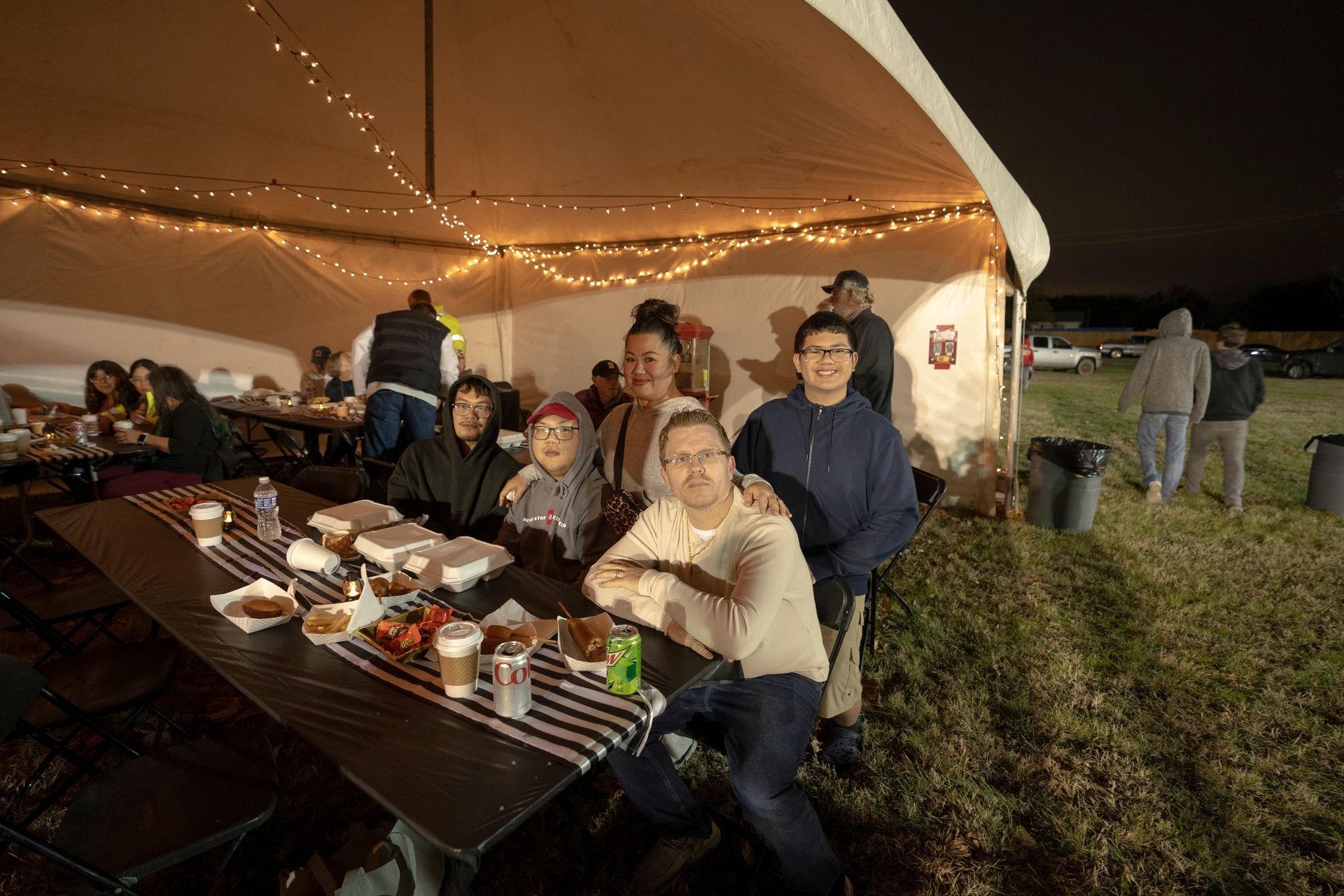 A group of people are sitting at a long table under a tent.