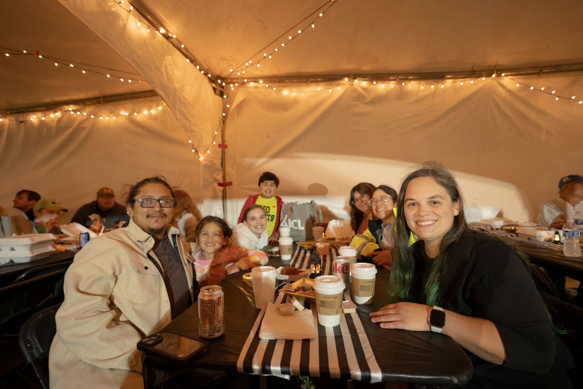 A group of people are sitting at tables under a tent.