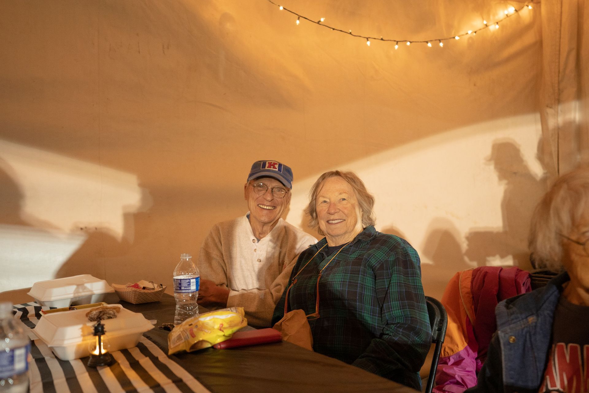 A man and a woman are sitting at a table in a tent.