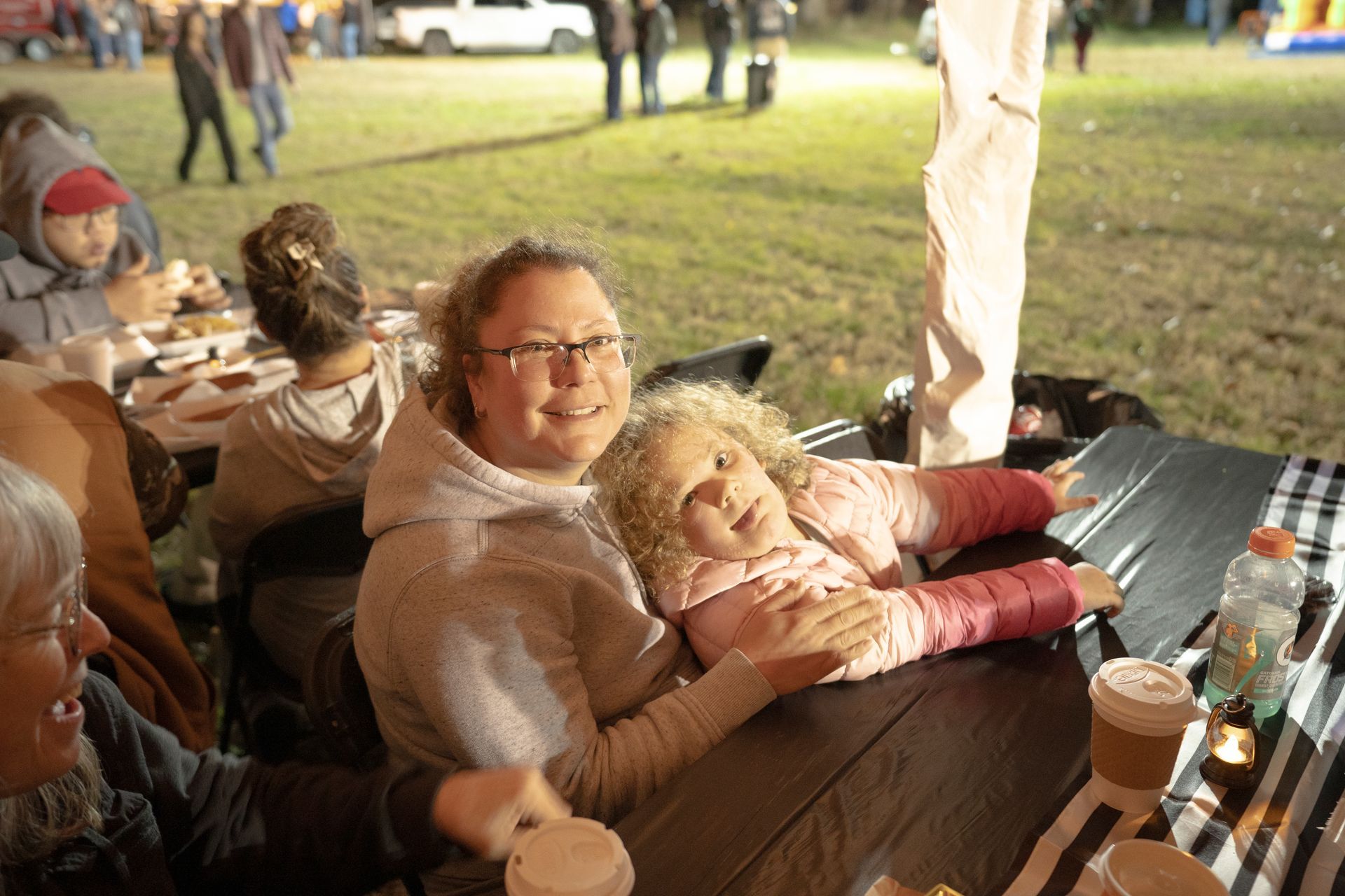 A woman is holding a little girl while sitting at a table.