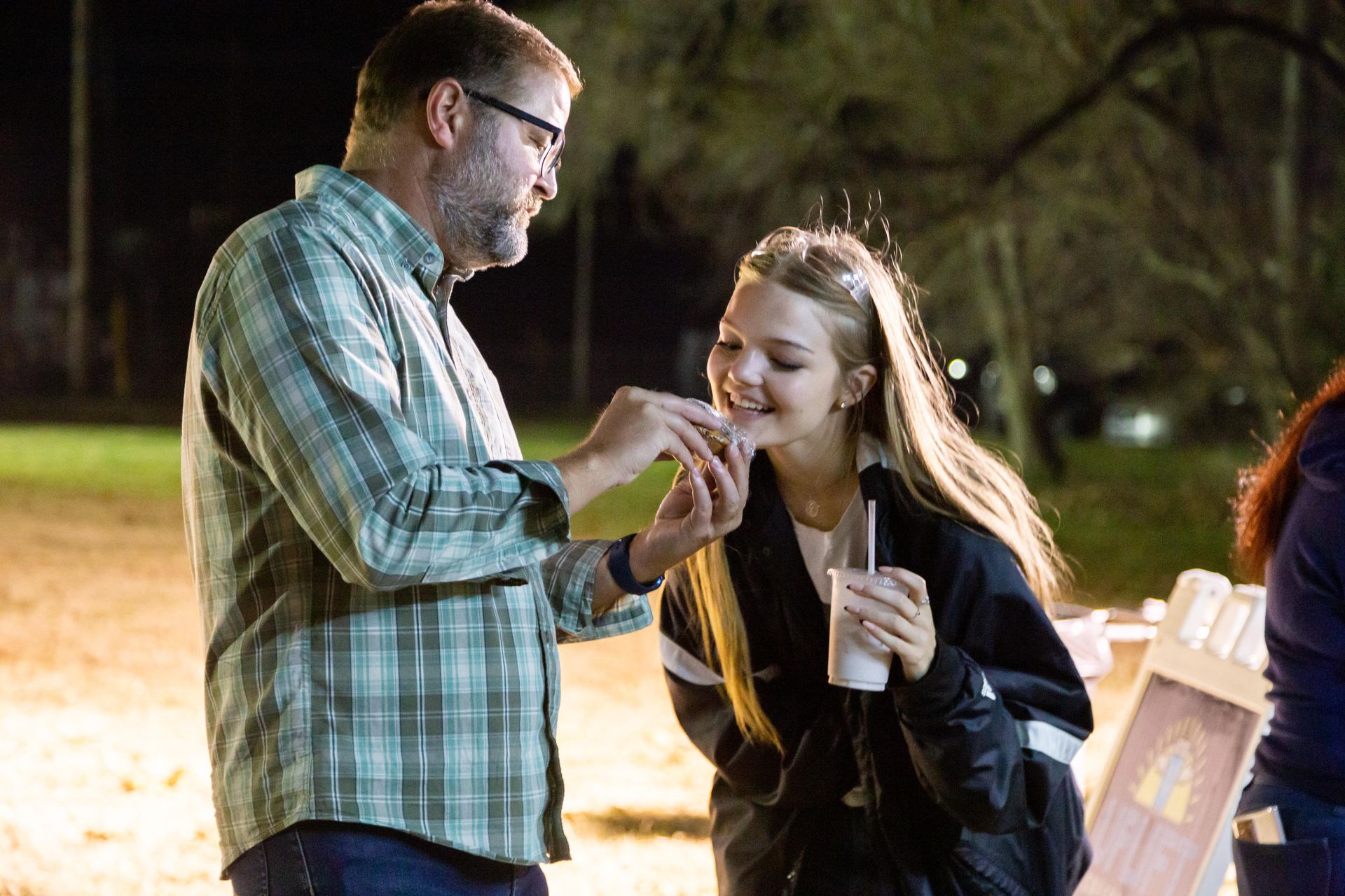 A father and daughter are standing together and smiling.