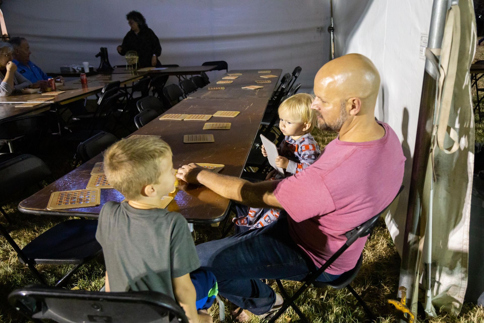 A father sits with hiskids and play BINGO.