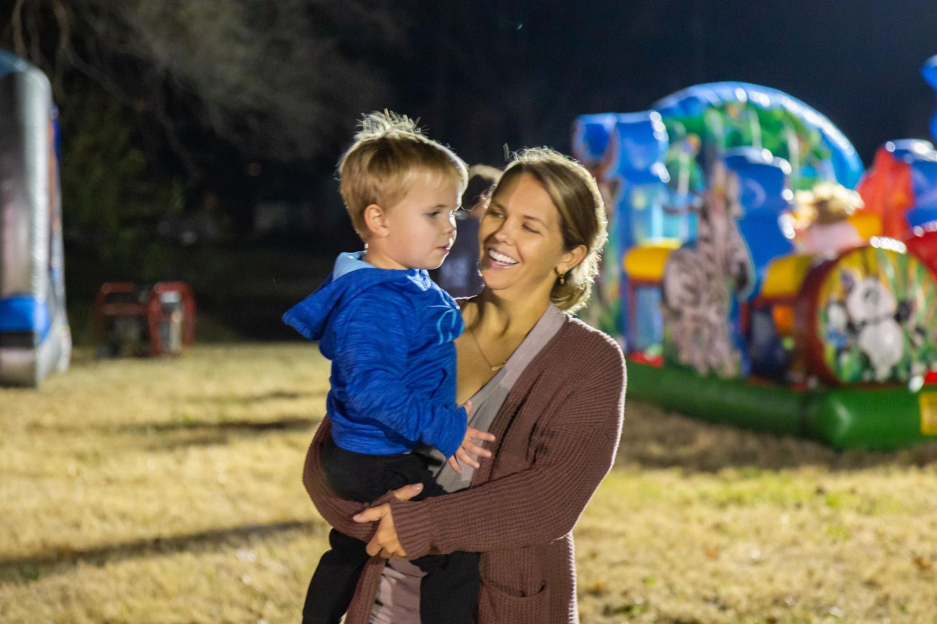 A mother holds a small boy and is smiling.