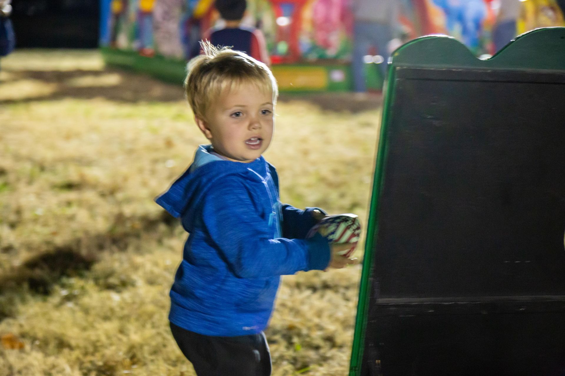 A cute little boy is playing a beam bag toss game.