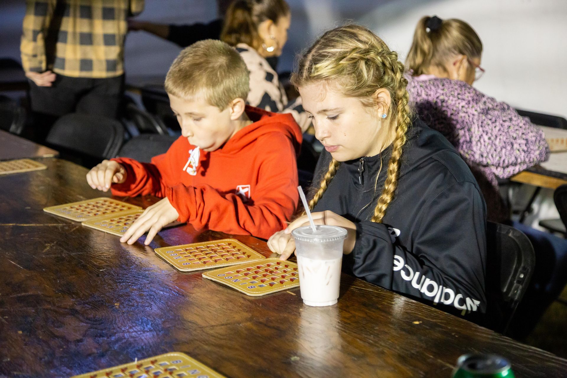 Two kids are sitting at a table and playing BINGO.