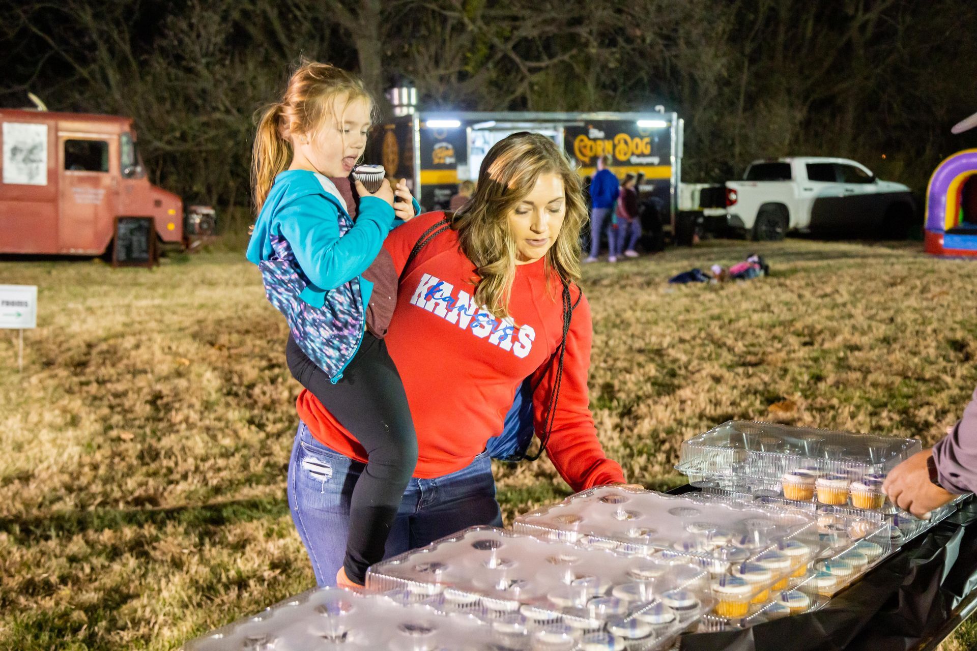 A mother and a daughter choose a snack from a table.