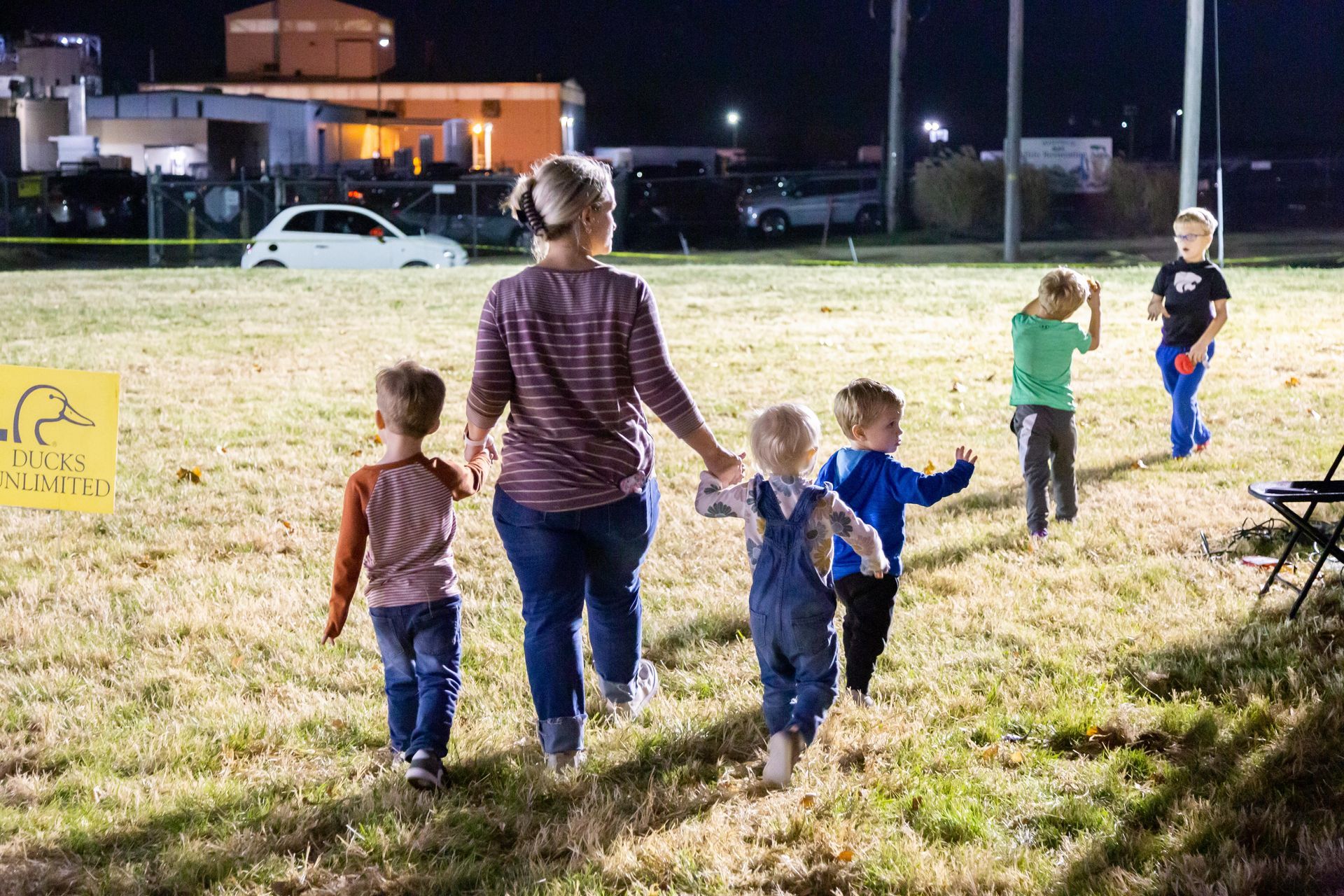A mother walks away with five kids walking with her.
