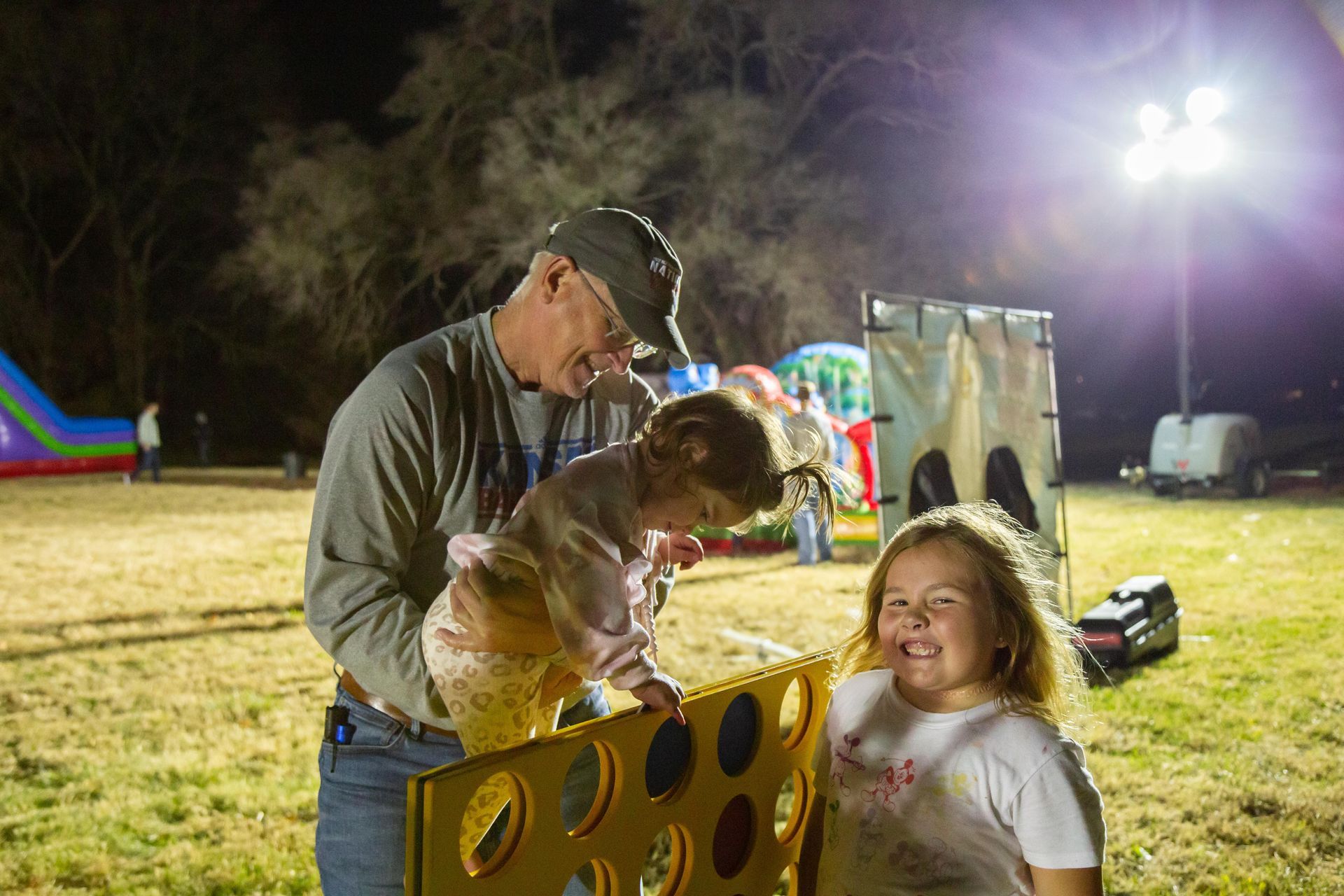 A man helps two kids play a large connect four game.
