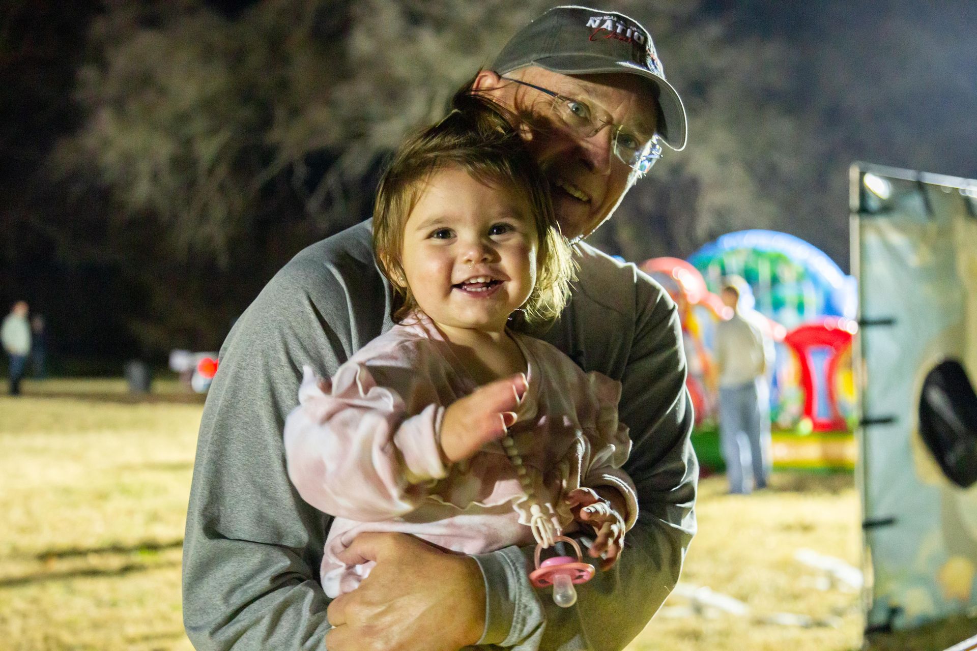 An adult holds a smiling and happy toddler.