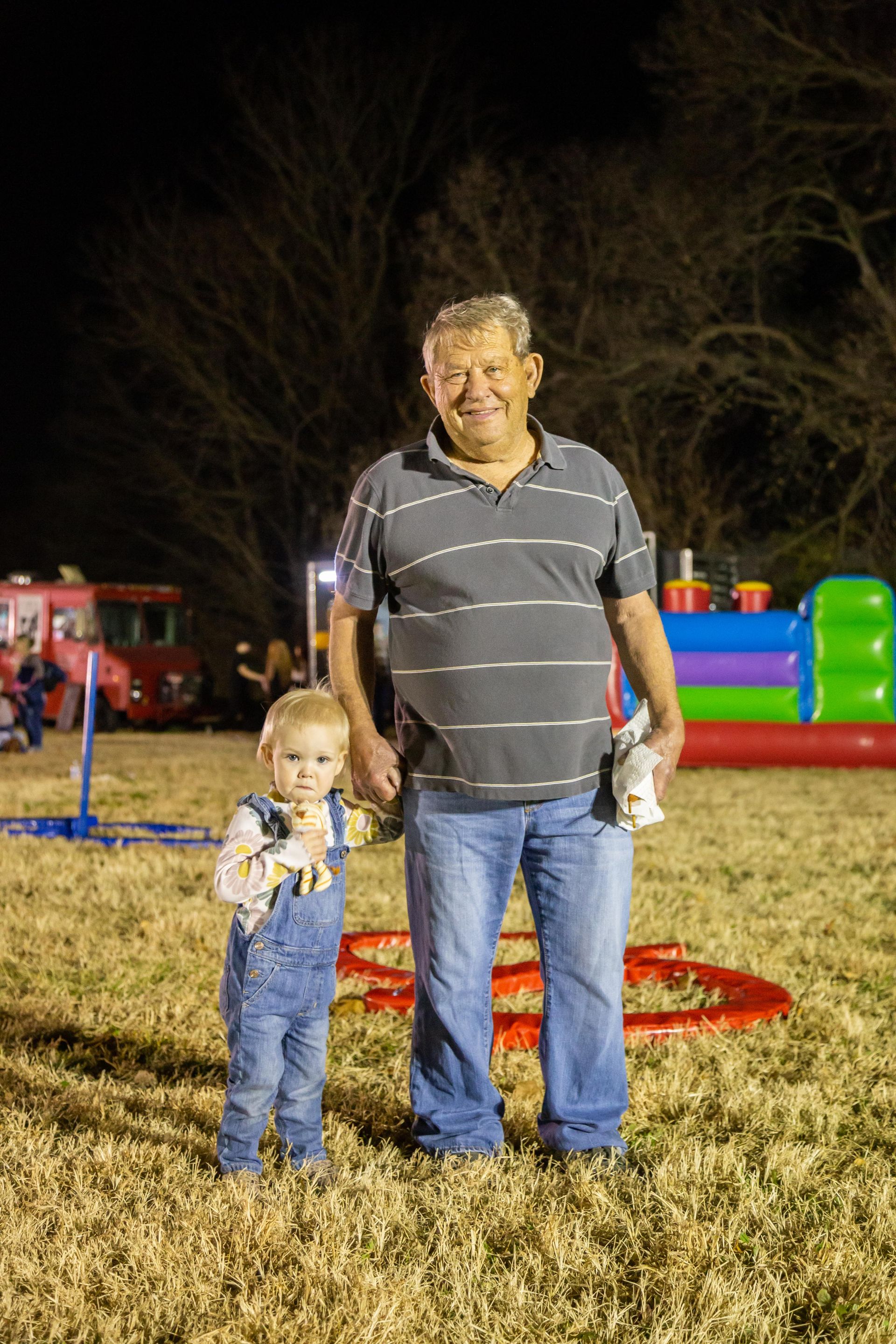 A man hold the hand of a small chaild and they are smiling.
