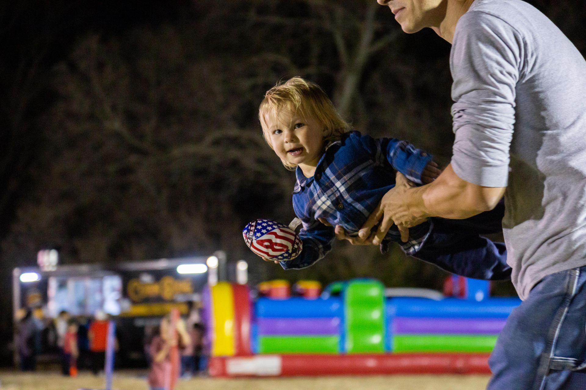 A dad helps his young son play a bean bag game.
