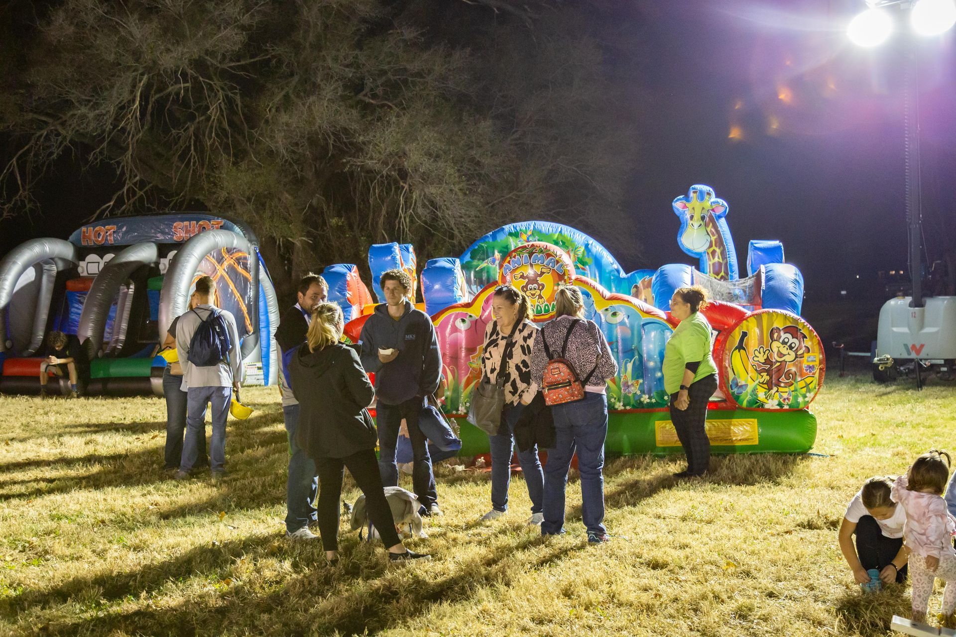 ICL family members are standing around talking with bounce houses in the background.